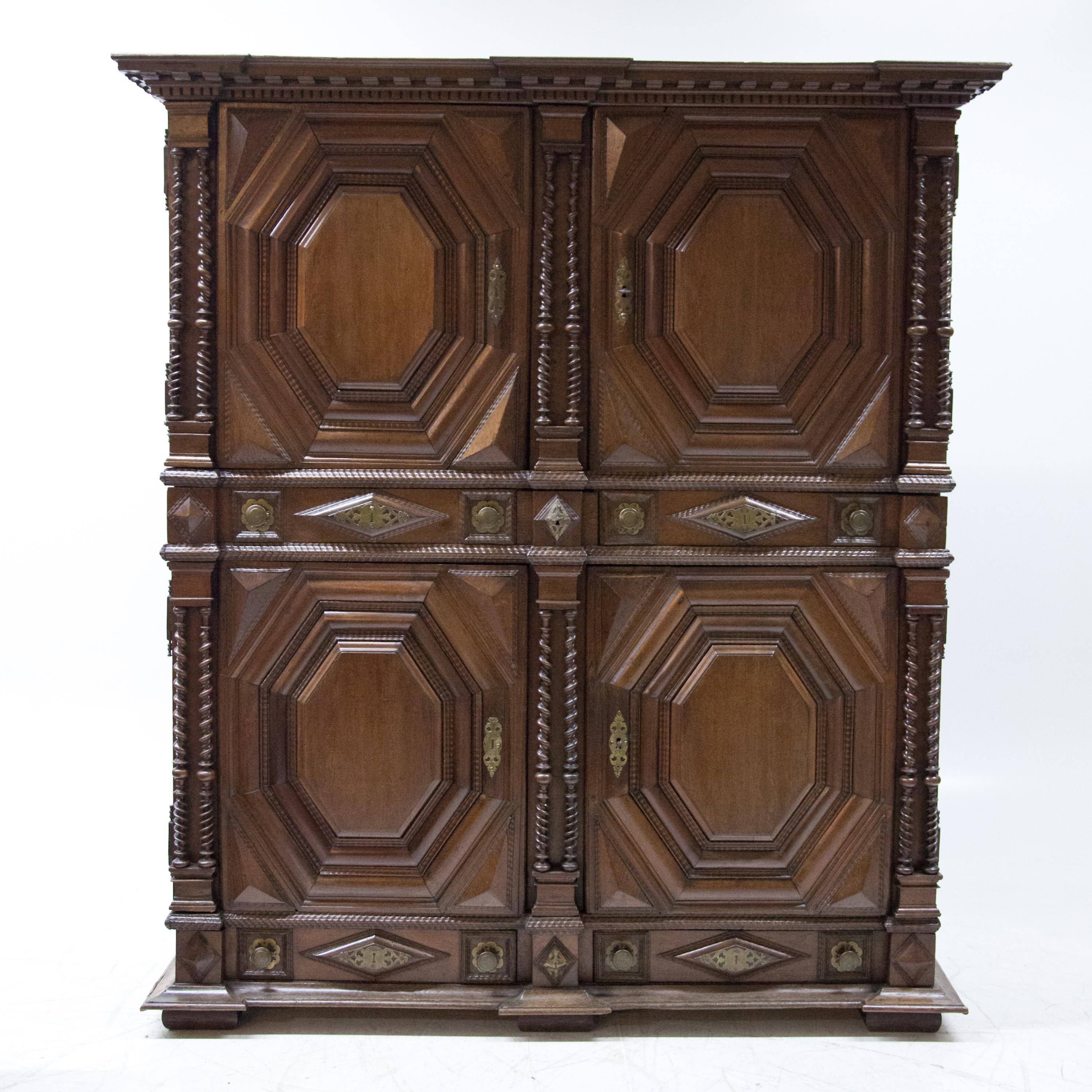 Large four-door oak cabinet with twisted double columns and multi-profiled cushion-shaped panels. The corners and stop are cranked and the flat cornice is decorated with a dentil bed mould. Below the doors there are three drawers and two large