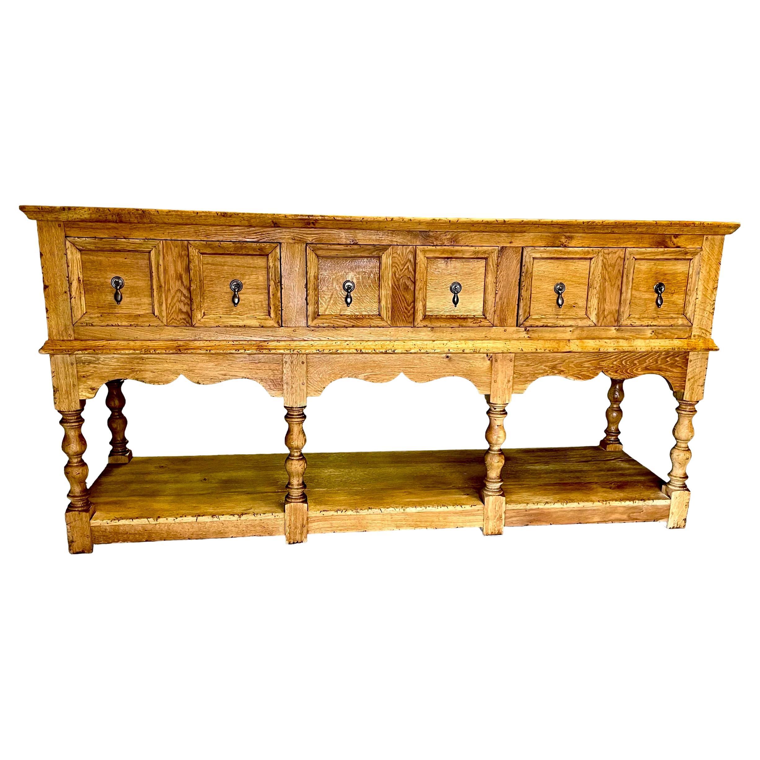 Jacobean Oak Sideboard Dresser Base with lower shelf.

English handmade in solid oak timber with turned legs,
with mitre cut drawer front moldings, shaped and panelled ends,
a solid oak back and solid oak drawer linings.

Offers great drawer storage