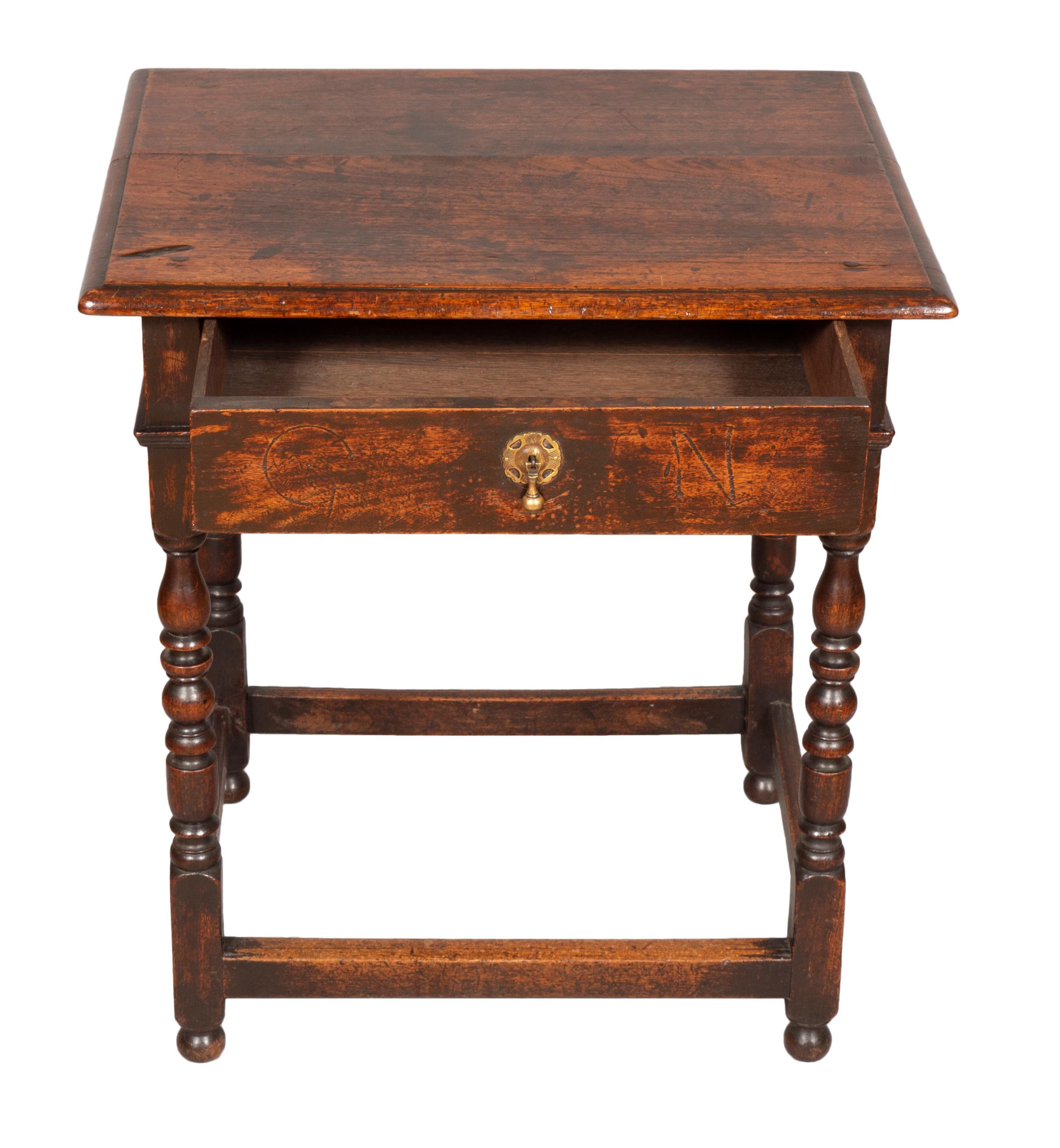 A cute table with great old color. Rectangular top over a drawer with tear drop pull and engraved initials , raised on turned legs with a box stretcher. Button feet.