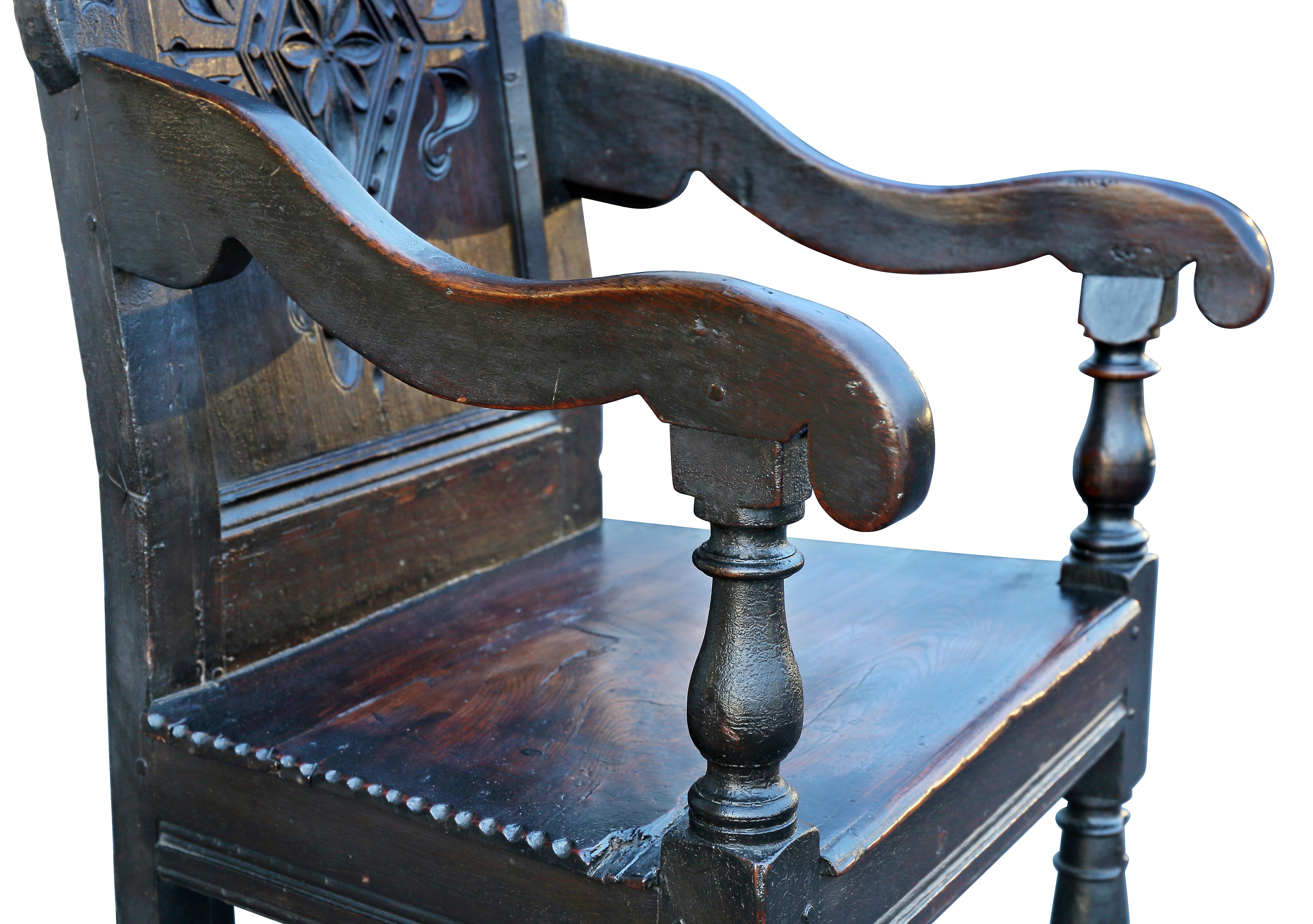 Double arched carved back over a panel with diamond panel, down scrolled arms, paneled seat raised on turned legs and box stretchers.