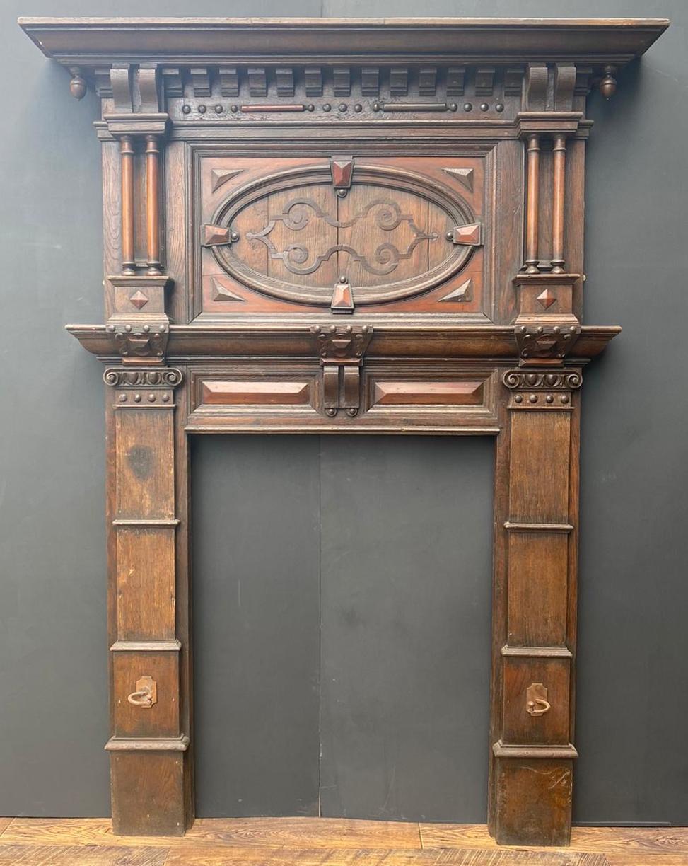 An English Jacobean period fire surround, salvaged from a property in Norfolk. Largely untouched, original condition. Of oak construction, with applied carved fruit-wood moldings.