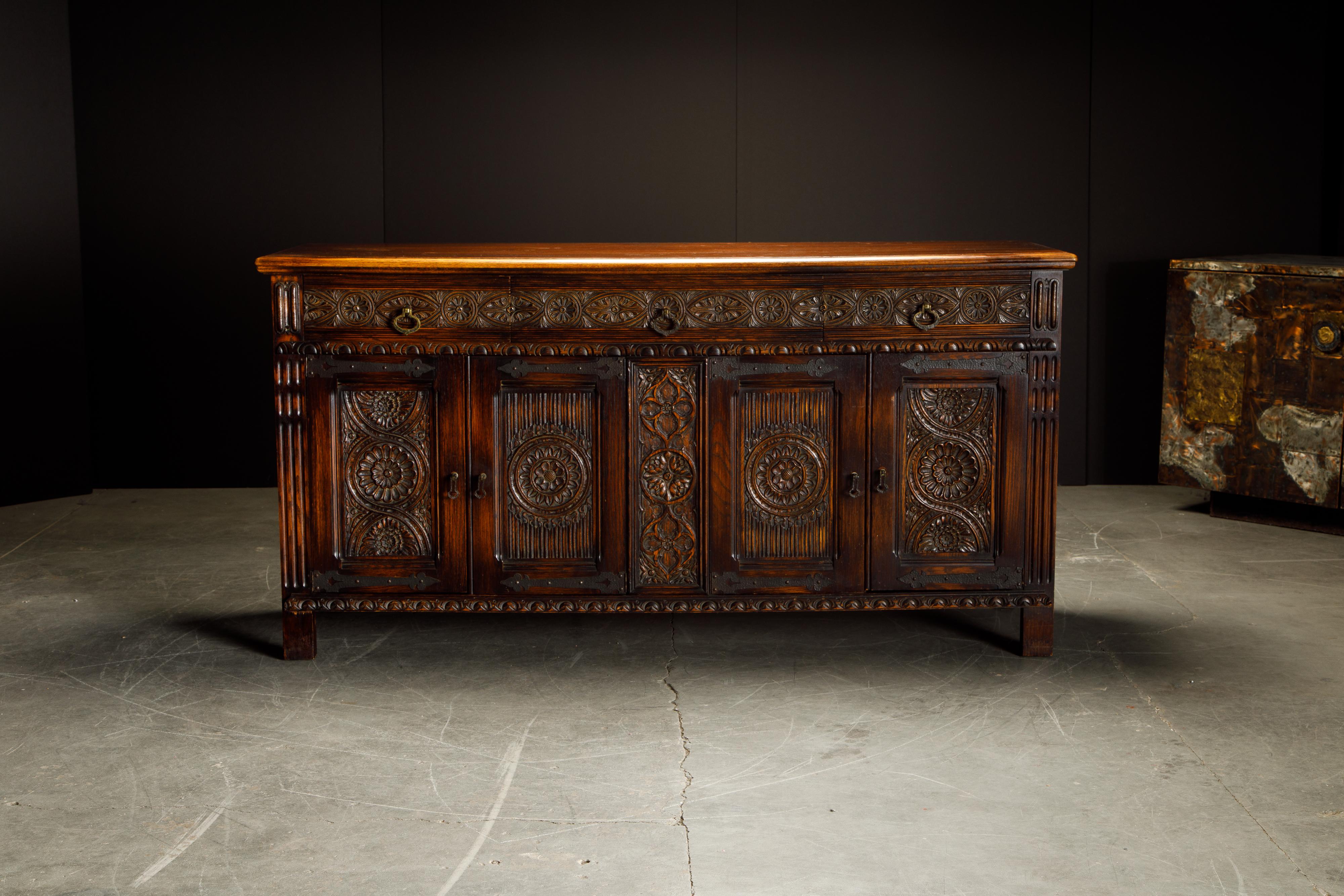 This gorgeous carved oak sideboard credenza is in the Jacobean Revival style with intricate detailing and ample storage space. We also have in other listings the matching pieces from this set which include a lowboy server / dry bar, highboy cupboard