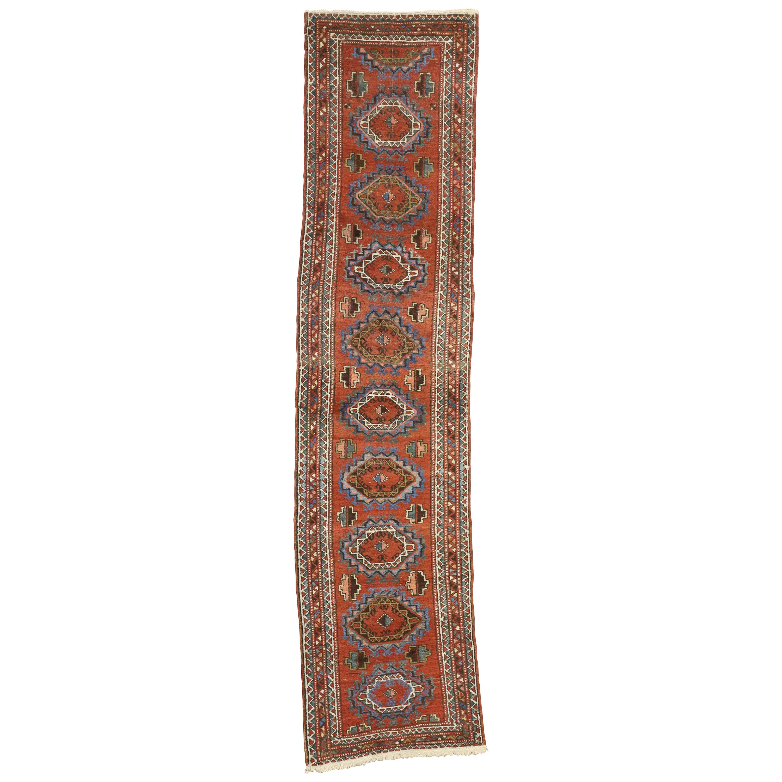 71542, Jacobean style antique Persian Heriz runner, narrow hallway runner. This hand knotted wool antique Persian Heriz runner features a series of stepped hexagonal medallions with ram’s horn hooks spread across an abrashed red field. Cruciform