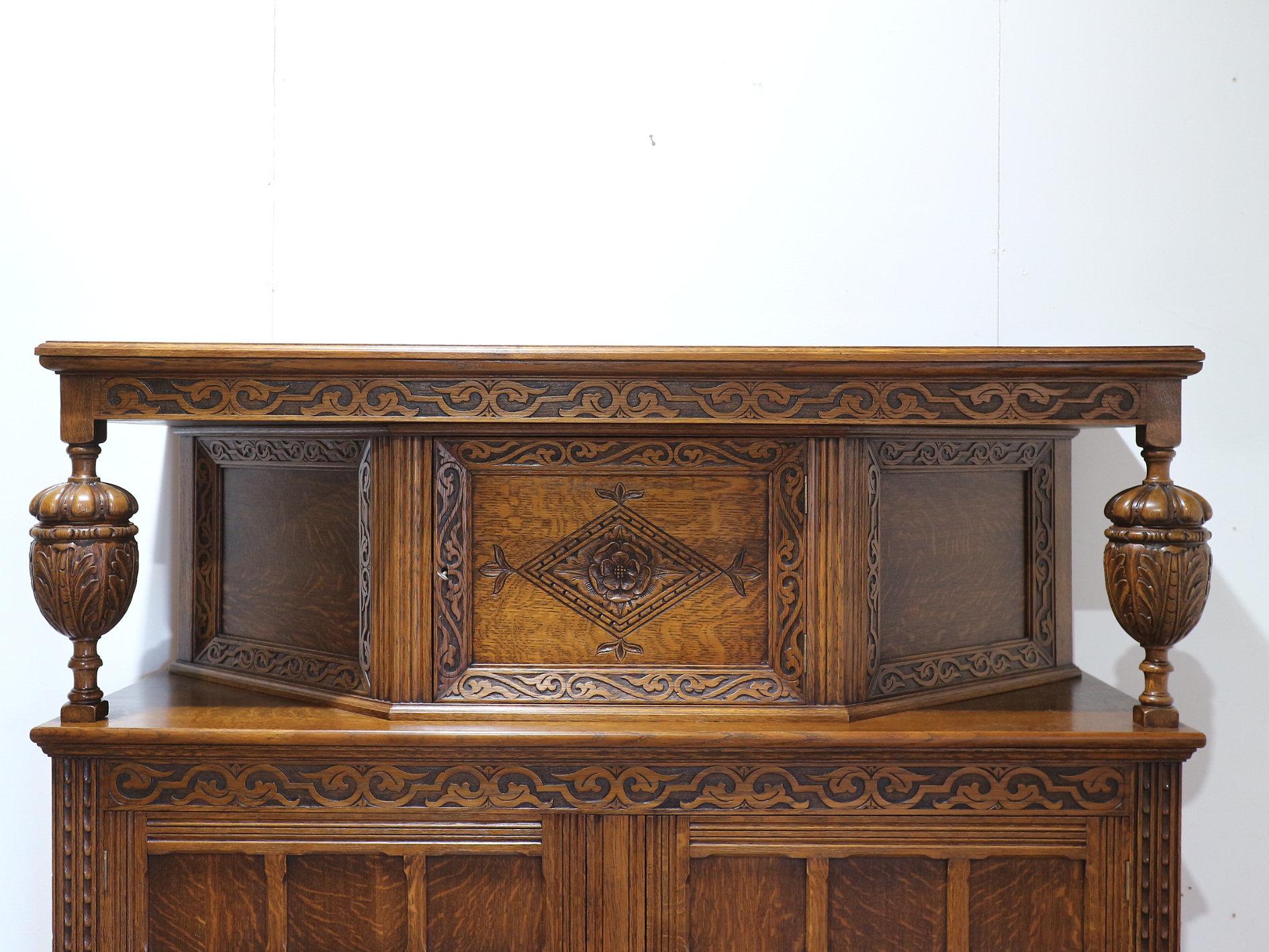 Discover the elegance of an Early 20th Century Jacobean Style Court Cabinet at Mid Century Traders. This oak carved cabinet showcases a stunning design that resonates with timeless craftsmanship, making it a perfect center piece for any