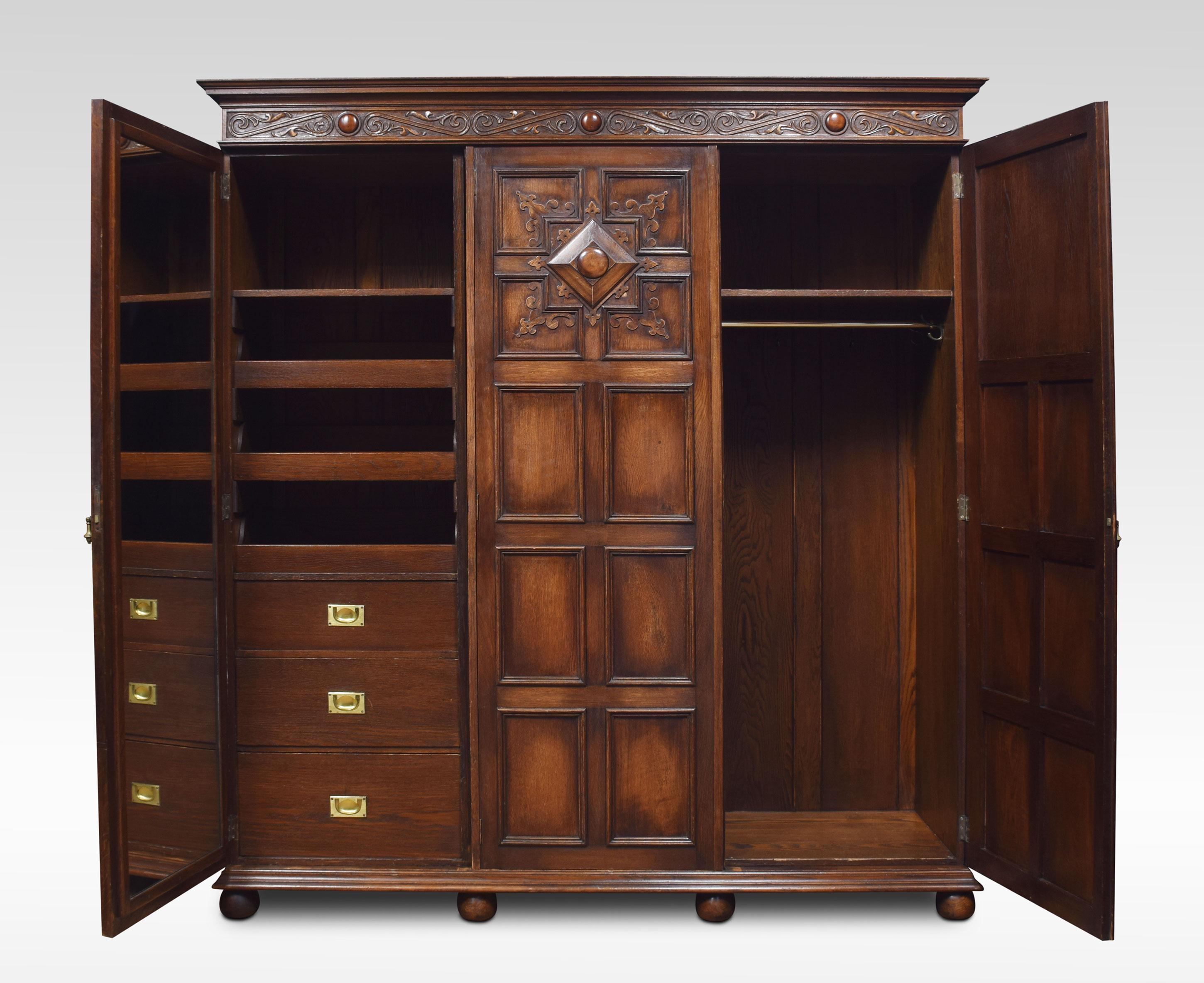 Large solid oak three-door compactum wardrobe. The moulded cornice with blind fret freeze above three geometric paneled doors opening to reveal an internal mirror, large hanging area to one side the other fitted with three drawers and two linen