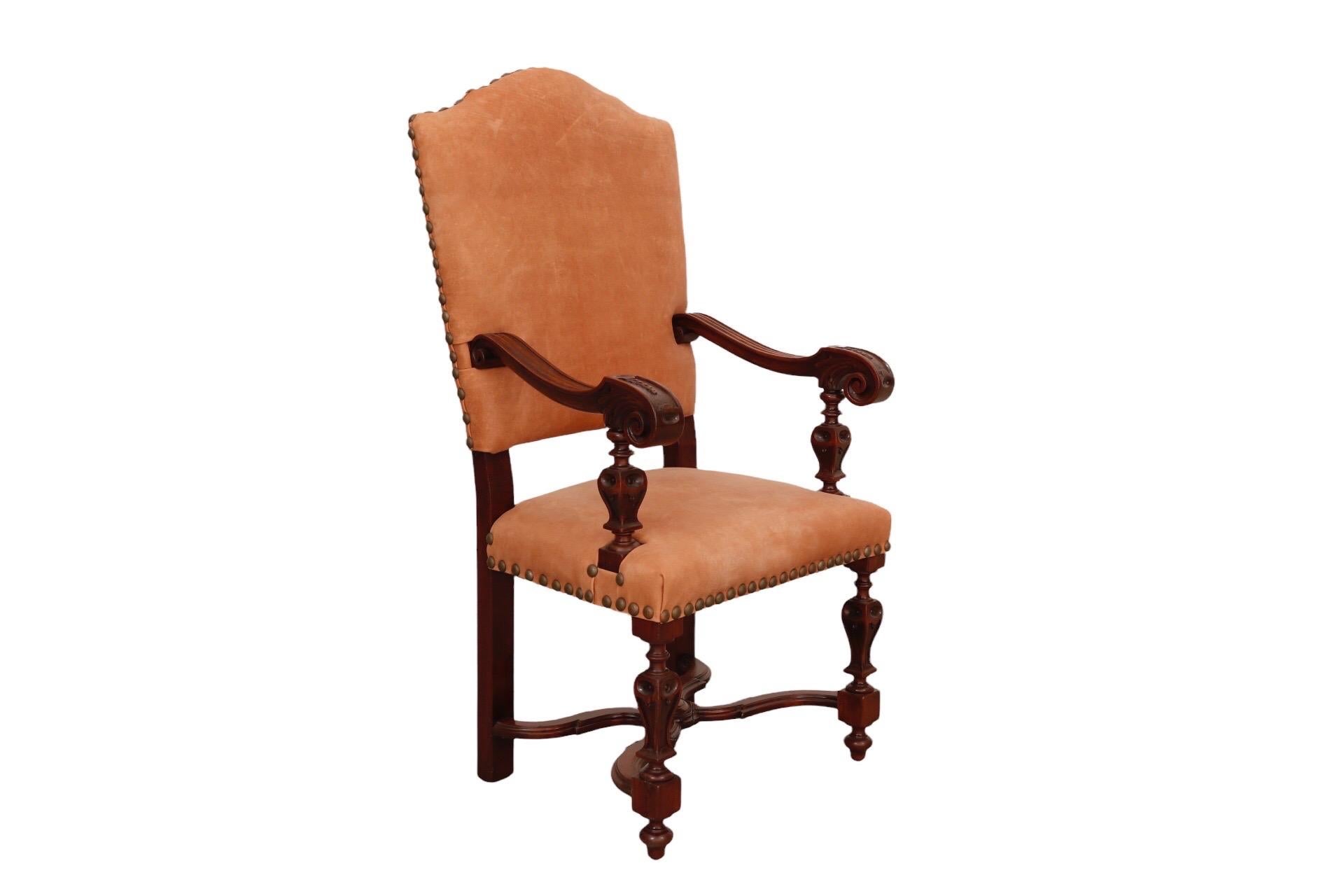 Un fauteuil en cuir de style jacobéen datant de la fin des années 1800. Fabriqué en acajou, l'assise et le dossier sont recouverts de cuir fixé par de grosses têtes de clous. Les bras en roseau sont sculptés de volutes à chaque extrémité et décorés