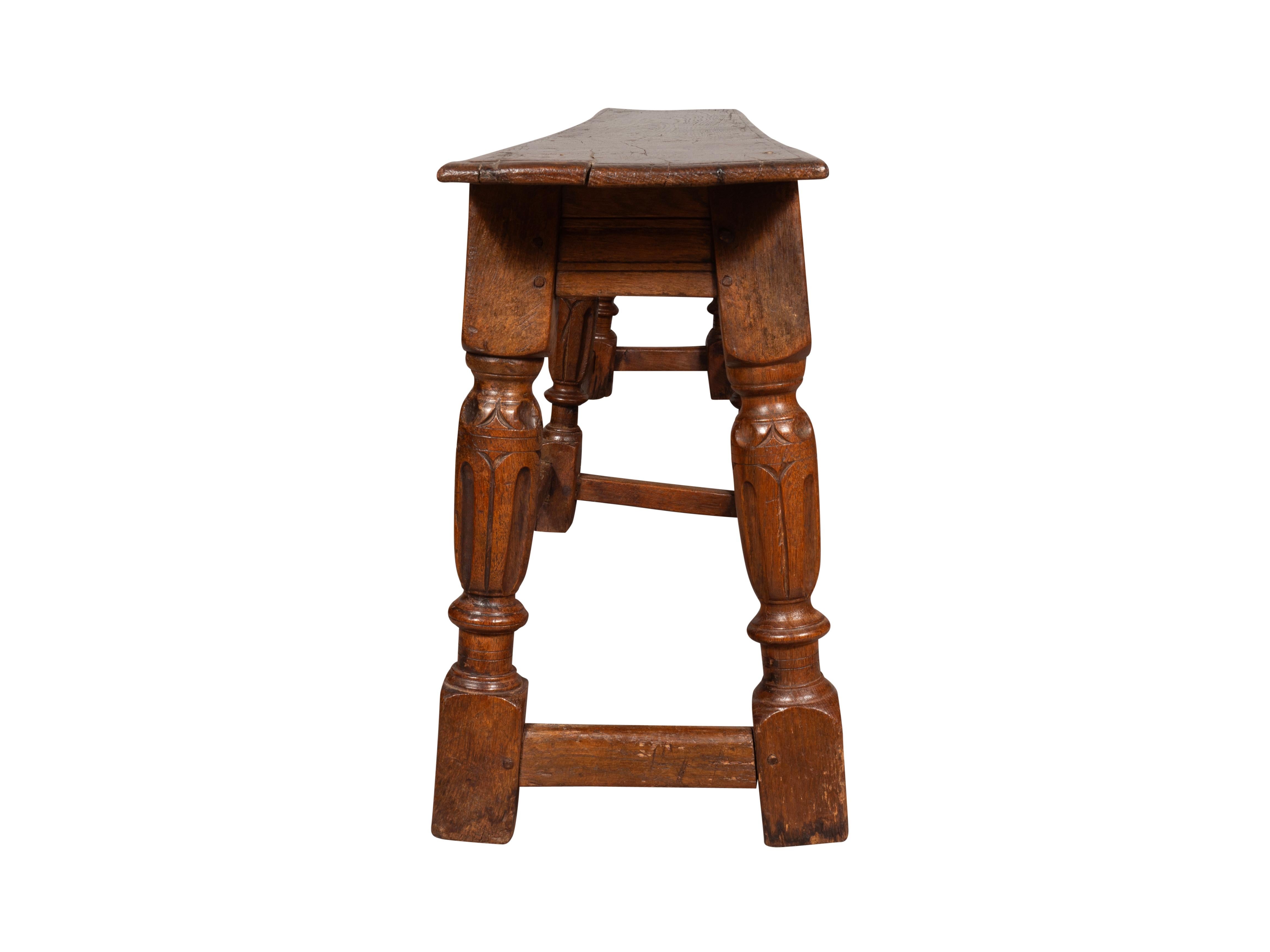 Constructed cleverly using old elements with good rich brown patina. Rectangular single board seat and conforming carved frieze supported on six turned legs joined by box stretchers.