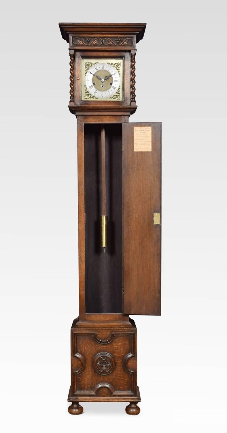 Jacobean style oak grandmother clock having eight day movement chiming on gongs, the silvered chapter ring with Roman numerals and scroll and floral cast spandrel mounted corners, the hood with carved foliate frieze. Enclosed by glazed hood door