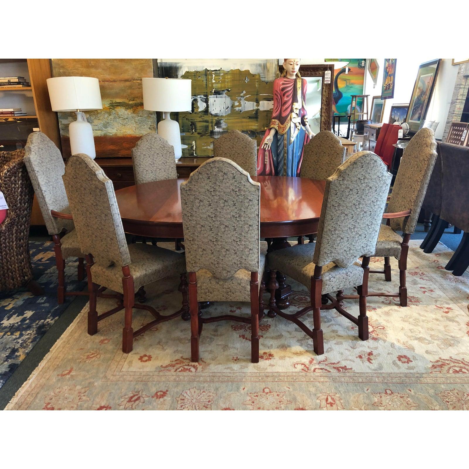A Jacobean dining set. Silhouettes reference traditional English style in a warm transitional form. Contract grade leaf patterned fabric add an organic and durable touch to eight dining chairs. Scrolled woodwork showcased on the arms of two