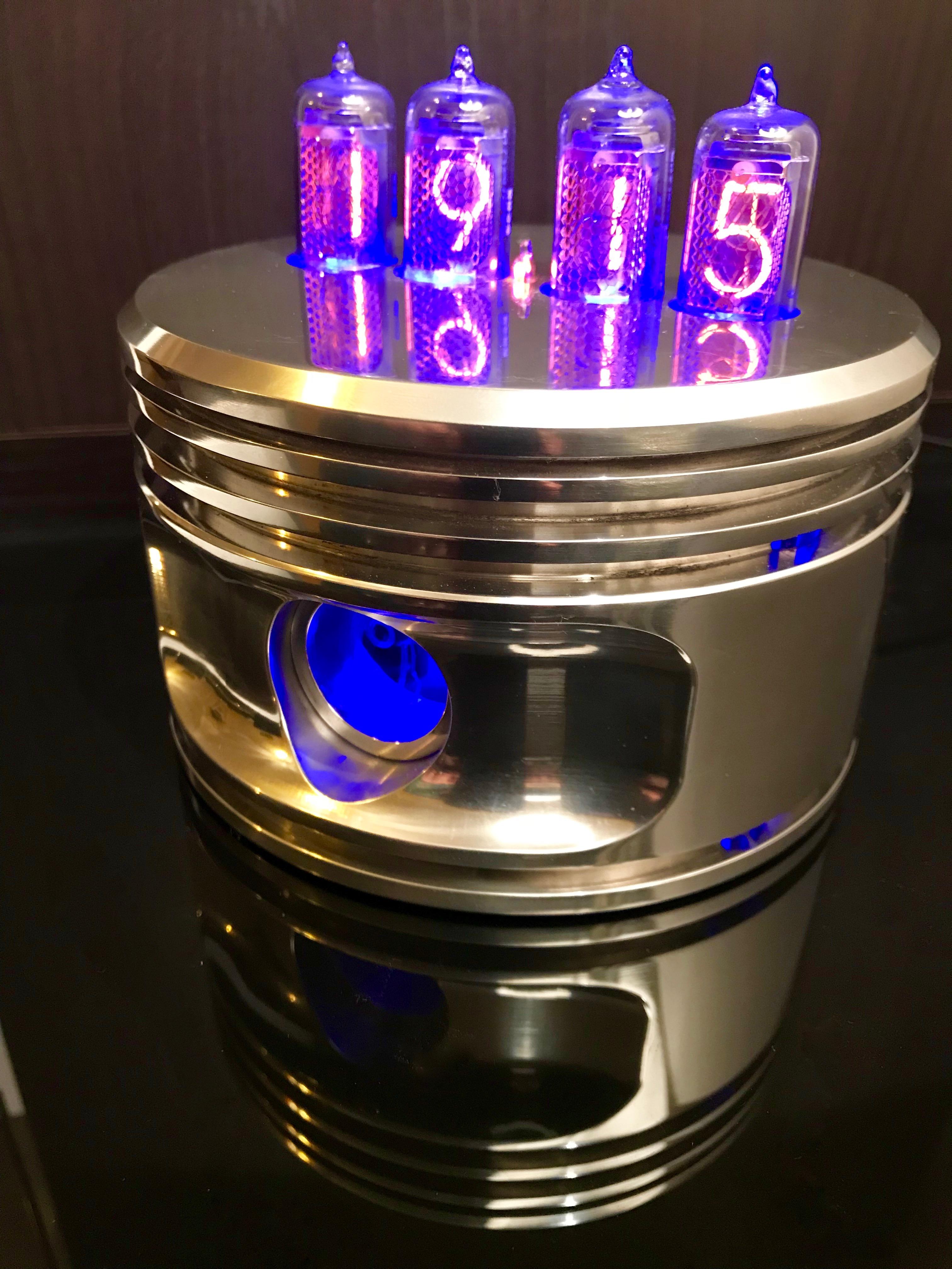 A highly polished Piston from a WWII Jacobs R-755, fitted with 4 Nixie tubes to clearly show the time, 24 or 12 hours with many options such as seconds , night dim, colour display options, brightness etc.

A beautiful unique clock. 
The Nixie