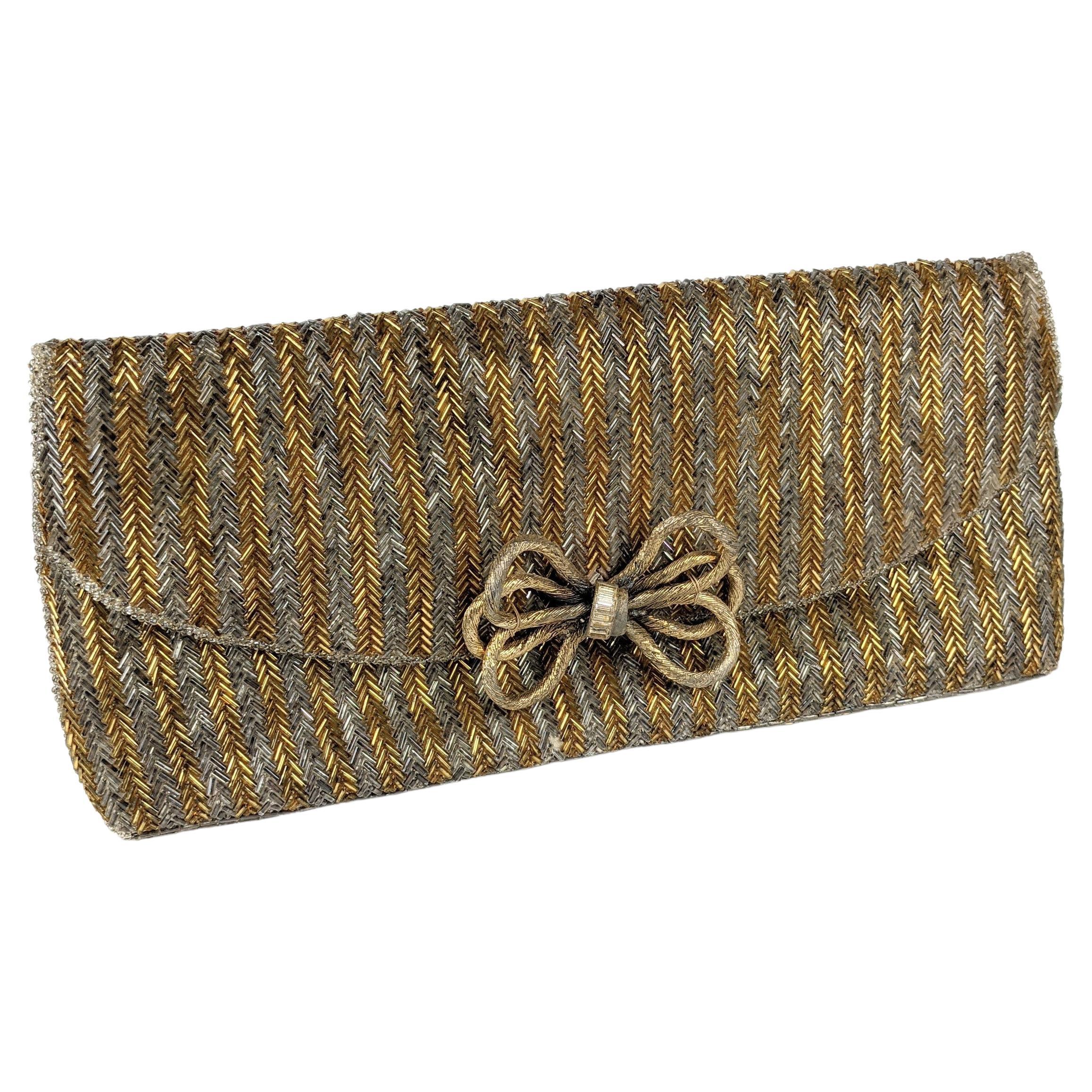 Jacomo Paris bugle beaded clutch striped in gold and silver. Beautiful quality completely chevron beaded with gilt metal bow ornament with baguette stones. Magnetic closure. 
1980's France.   11