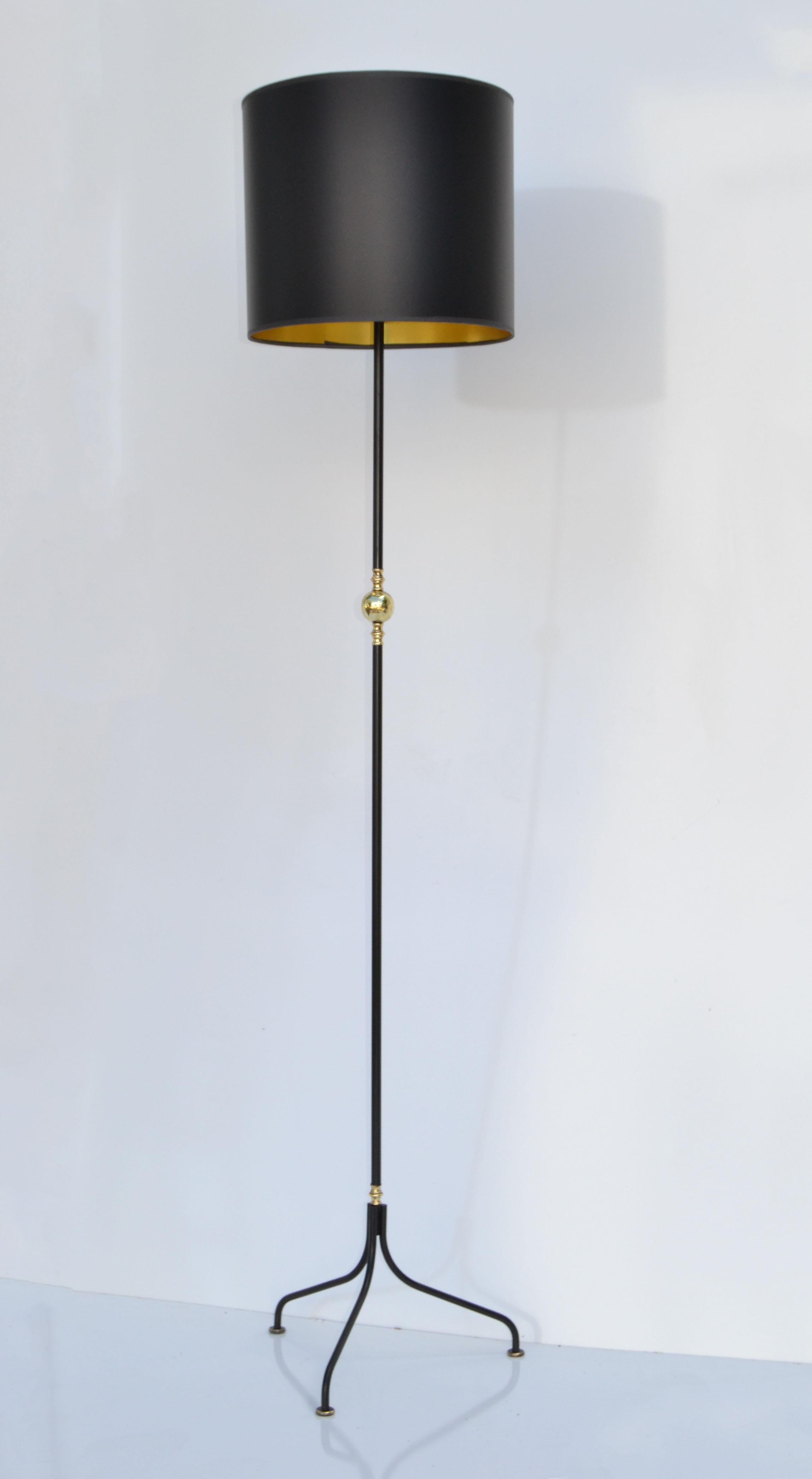 Superb Jacques Adnet Style Floor Lamp in Brass and black finished Iron on a decorative Tripod Base with Brass Glides. 
Comes with custom made Black & Gold Paper Drum Shade.
Mid-Century Modern Design from France and made 1950.
US rewired and in