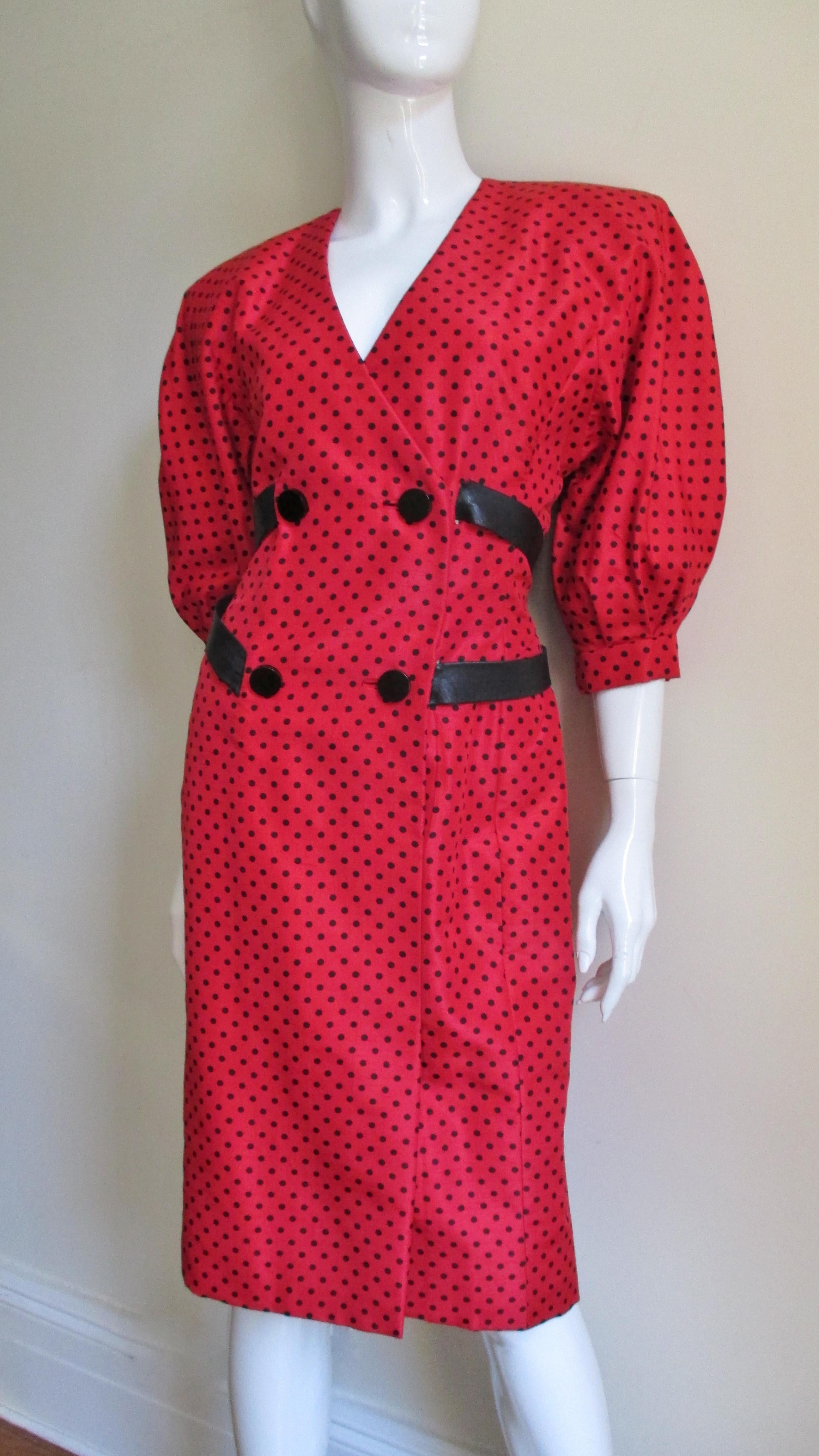 A fabulous red silk dress with black dots by French designer Jacqueline de Ribes.  It has a double breasted wrap style closing with round black buttons and bound buttonholes and fabulous black leather straps wrapping around the dress above and below