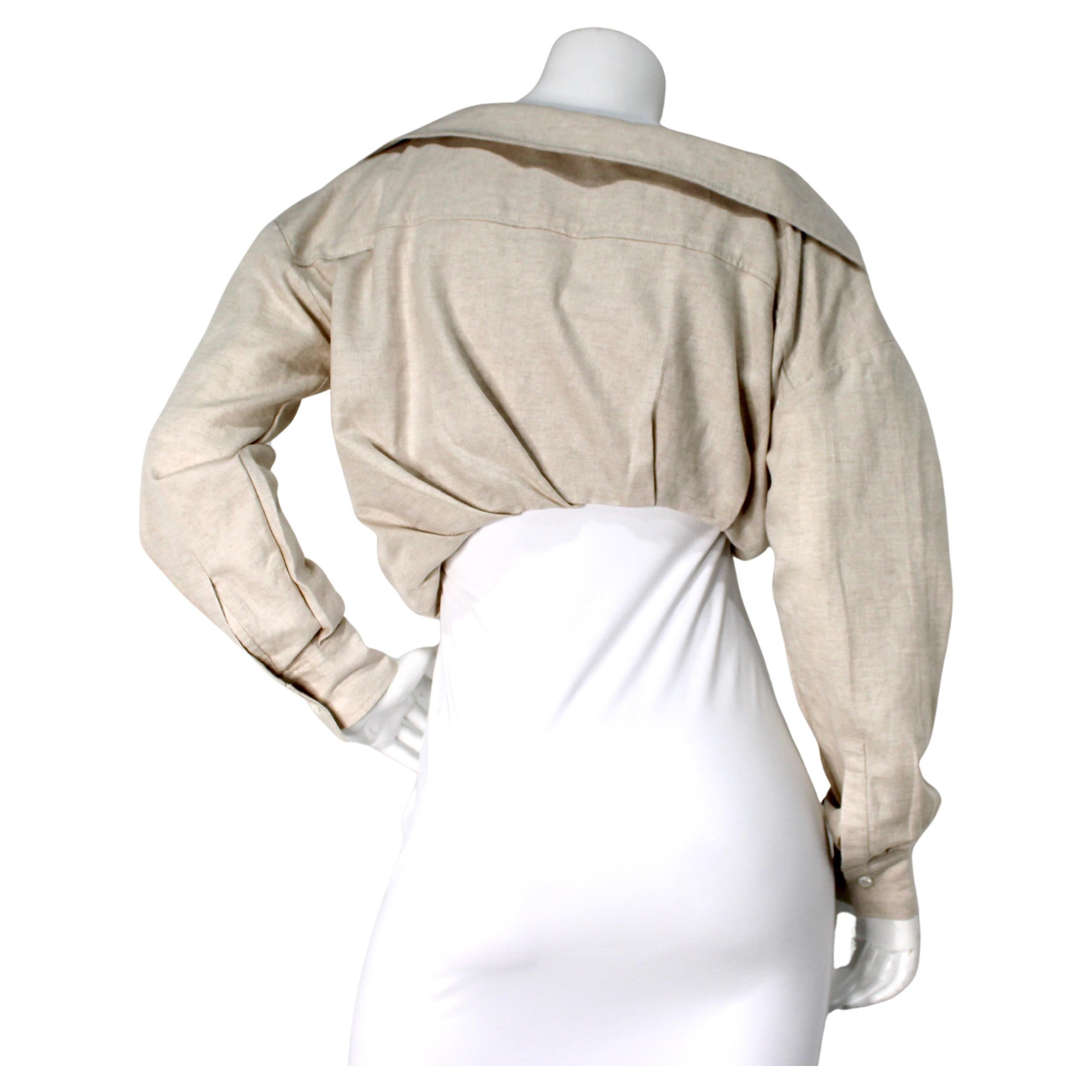 Das beigefarbene L'ANNÉE 97 Asymmetric Cropped Button-Up Shirt von Jacquemus ist ein auffälliges Stück, das modernen Minimalismus mit einem Hauch von Avantgarde verkörpert. Es ist aus Baumwolle und Leinen in einem neutralen Beigeton gefertigt und