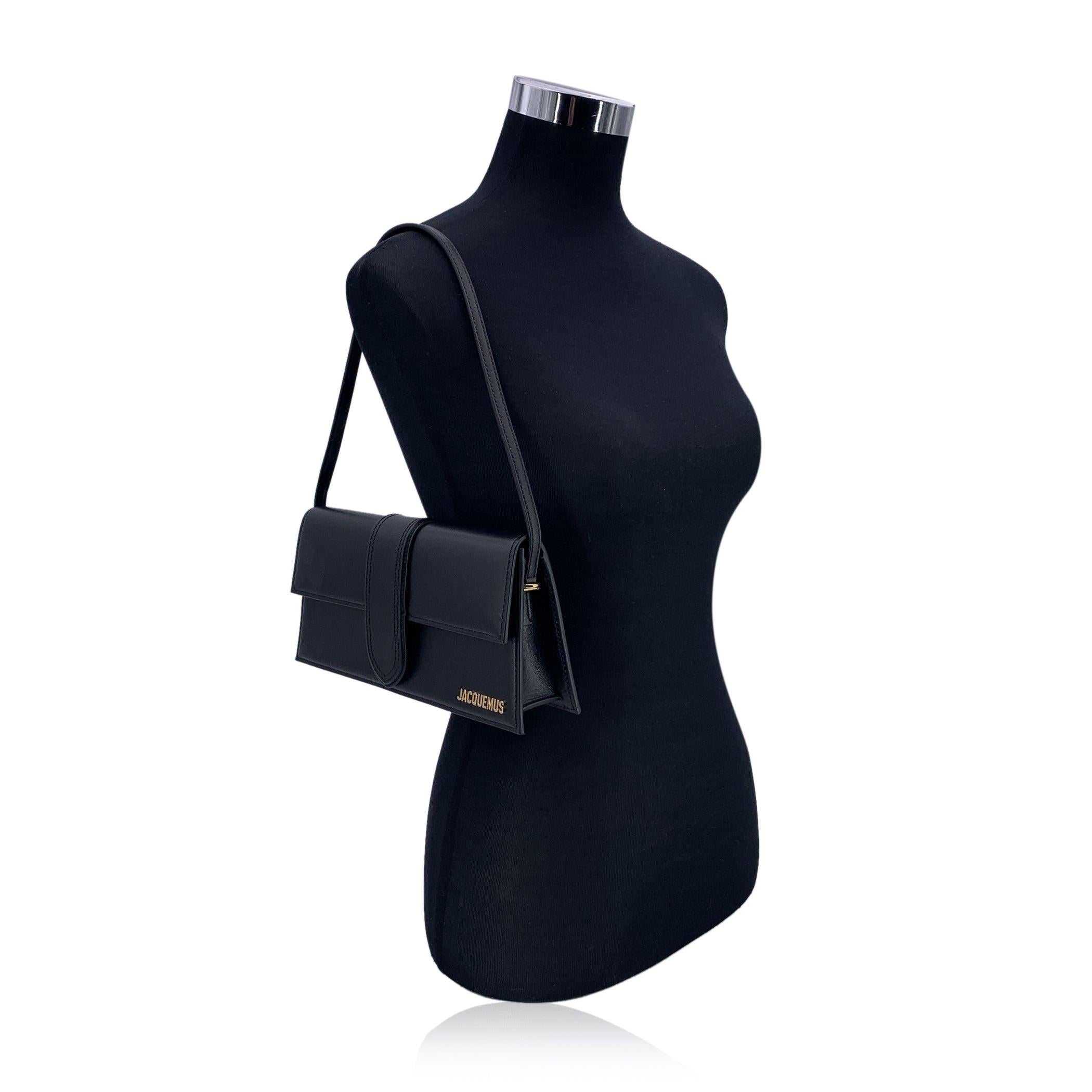 Jacquemus black leather Le Long Bambino Structured box bag. Gold metal logo on the front. Thin non-adjustable shoulder strap. Flap with magnetic button closure. 1 open pocket on the back. Beige canvas lining. 1 side open pocket inside. 'Jacquemus -