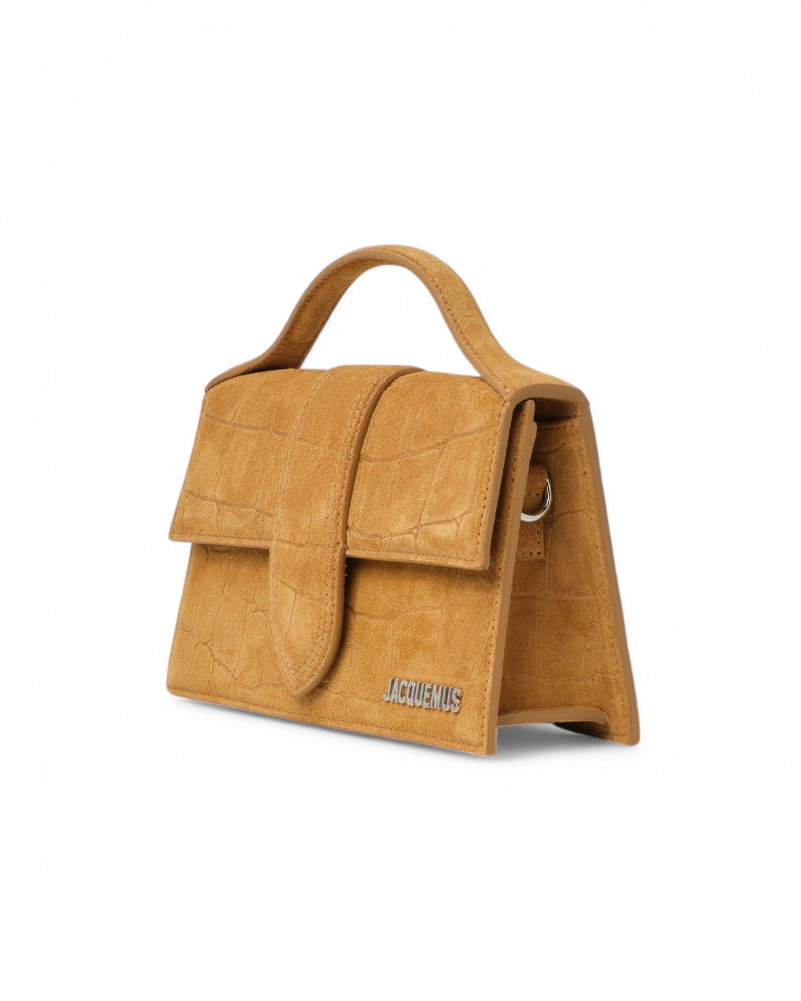 Borsa firmata Jacquemus, modello Le Grand Bambino, realizzata in tessuto scamosciato con effetto cocco  nella colorazione cammello con hardware dorati. Dotata di una patta frontale con chiusura a bottone calamitato, internamente rivestita in tela