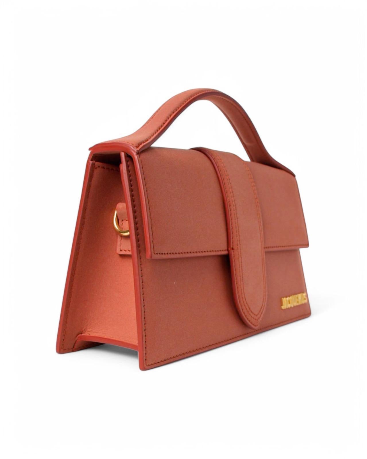 Jacquemus signature bag, model Le Grand Bambino, made of Nubuck leather in the clay coloring  with gold hardware. Featuring a front flap with magnetic button closure, internally lined with beige canvas, roomy for essentials. Munita di un manico