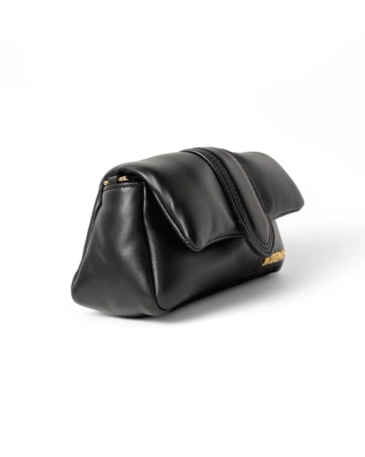 Borsa firmata Jacquemus, modello Le Petit Bambimou, realizzata in pelle nera con hardware dorati. Dotata di una patta frontale con chiusura magnetica, internamente rivestita in tela beige con piccola tasca, la borsa è capeinte per l’essenziale.