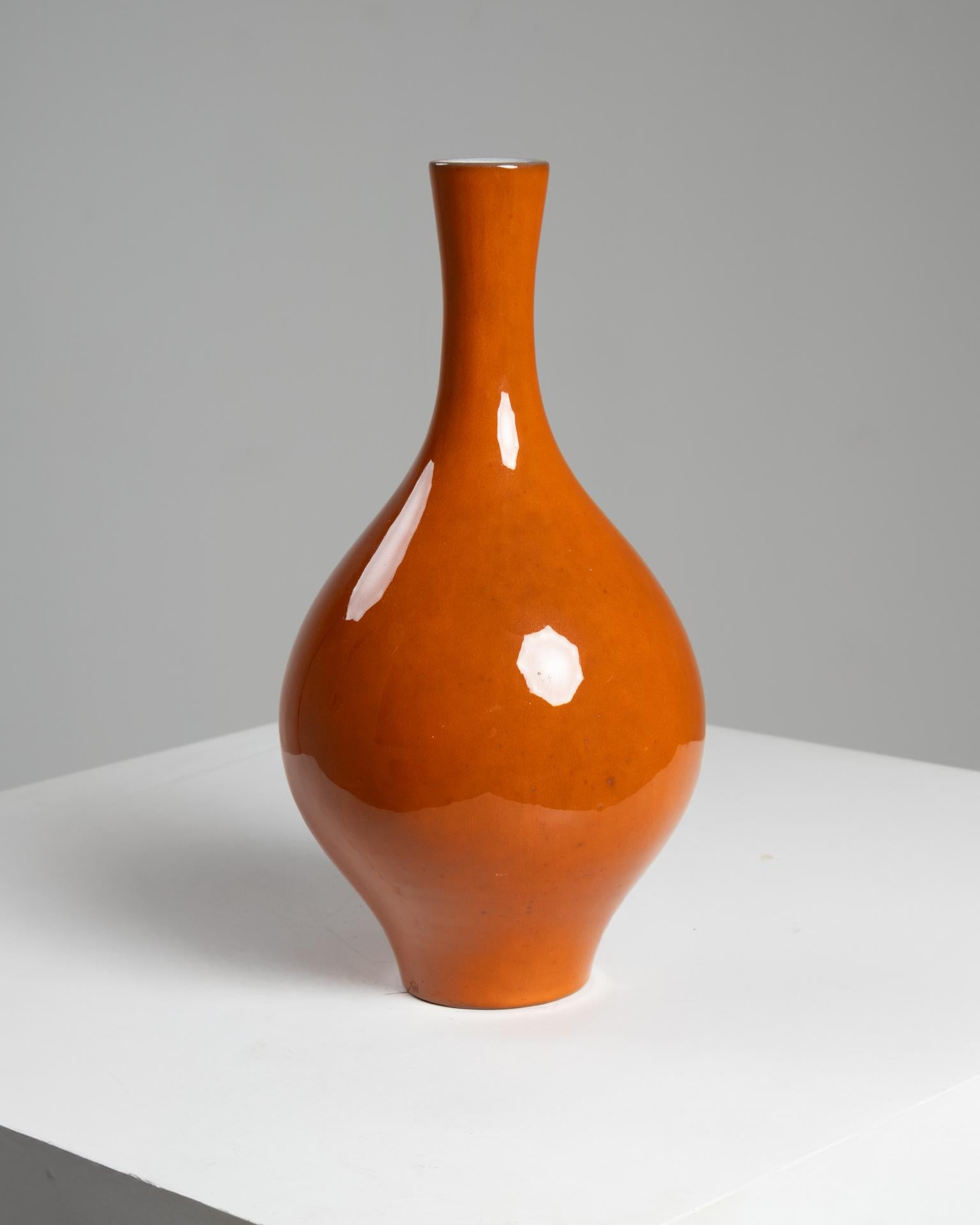 Este vibrante jarrón de cerámica esmaltada de color naranja fue creado por los renombrados ceramistas franceses Jacques (1926-2008) y Dani (1933-2010) Ruelland, figuras clave del movimiento cerámico francés de posguerra. Fabricada en Francia hacia