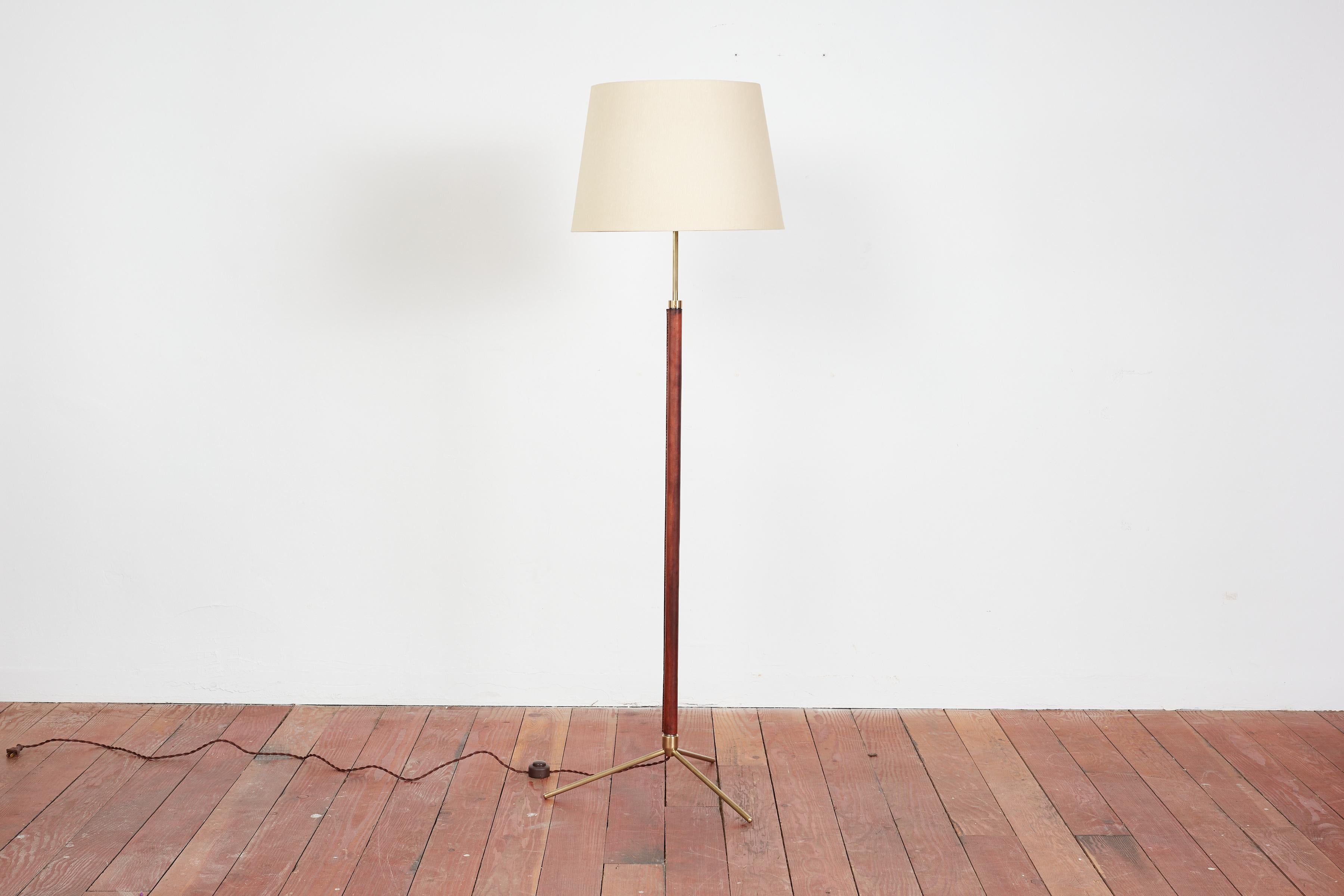 Handsome French floor lamp by Jacques Adnet.

Signature hand-stitched saddle Brown leather, contrast stitching, brass tripod base and new silk shade. 

Newly rewired. 