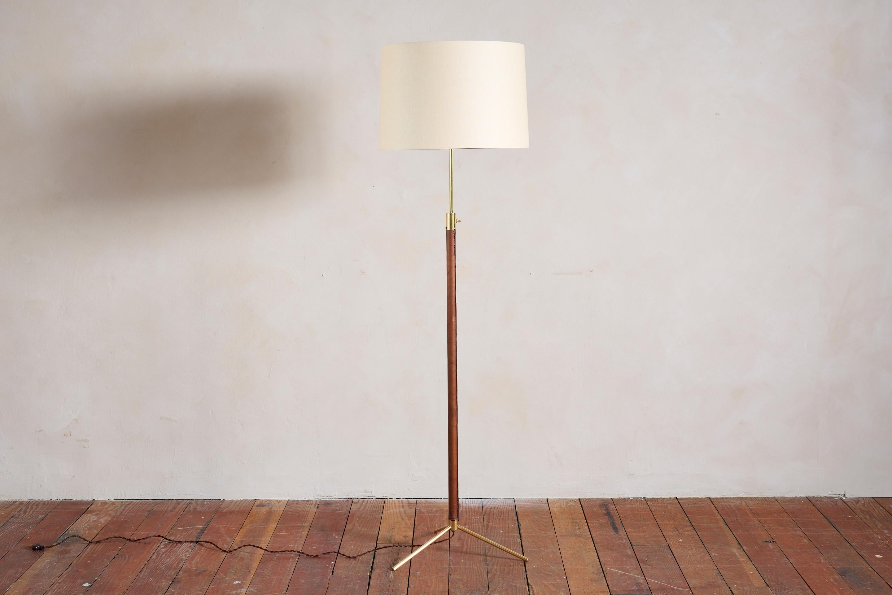 Beau lampadaire français de Jacques Adnet.

Cuir marron sellier cousu main, coutures contrastées, pied tripode en laiton et nouvel abat-jour en lin. 

Nouvellement recâblé. 