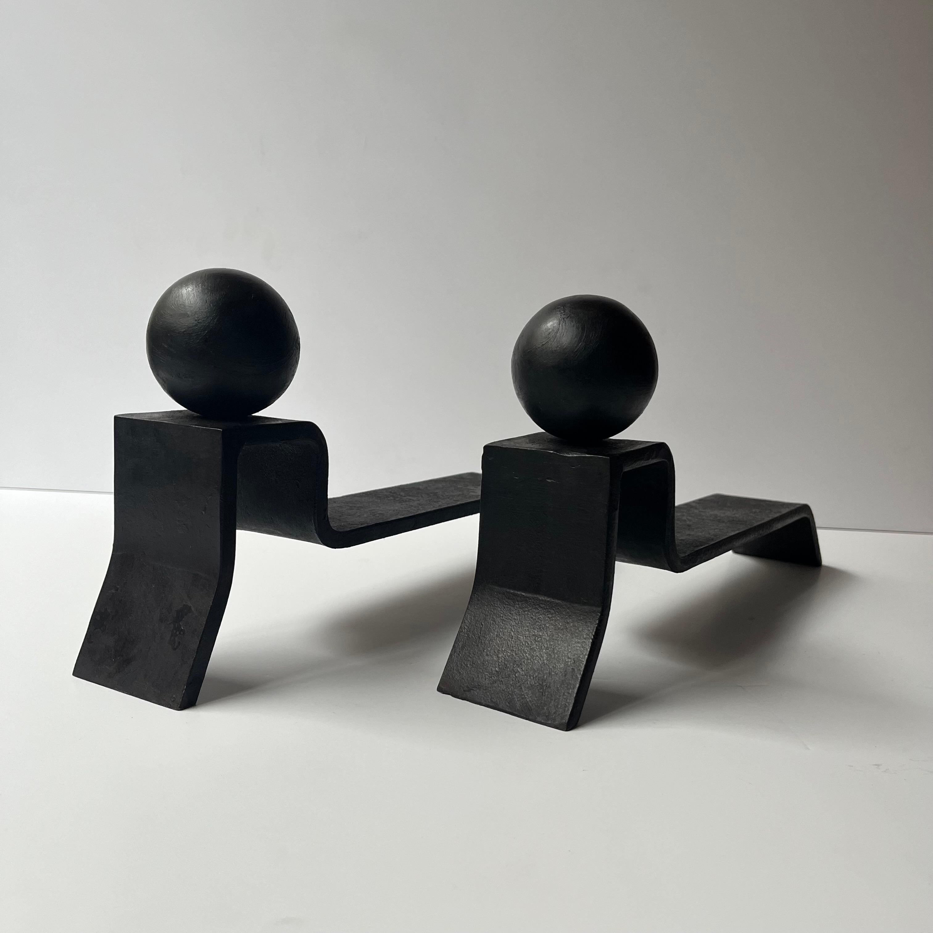A pair of Minimalist Andirons by Jacques Adnet (1900 -1984).
With their simple, modern shape, clean lines and dark matte finish, these sculptural forms strike a balance between Adnet’s love for both modernity and tradition, while the spherical