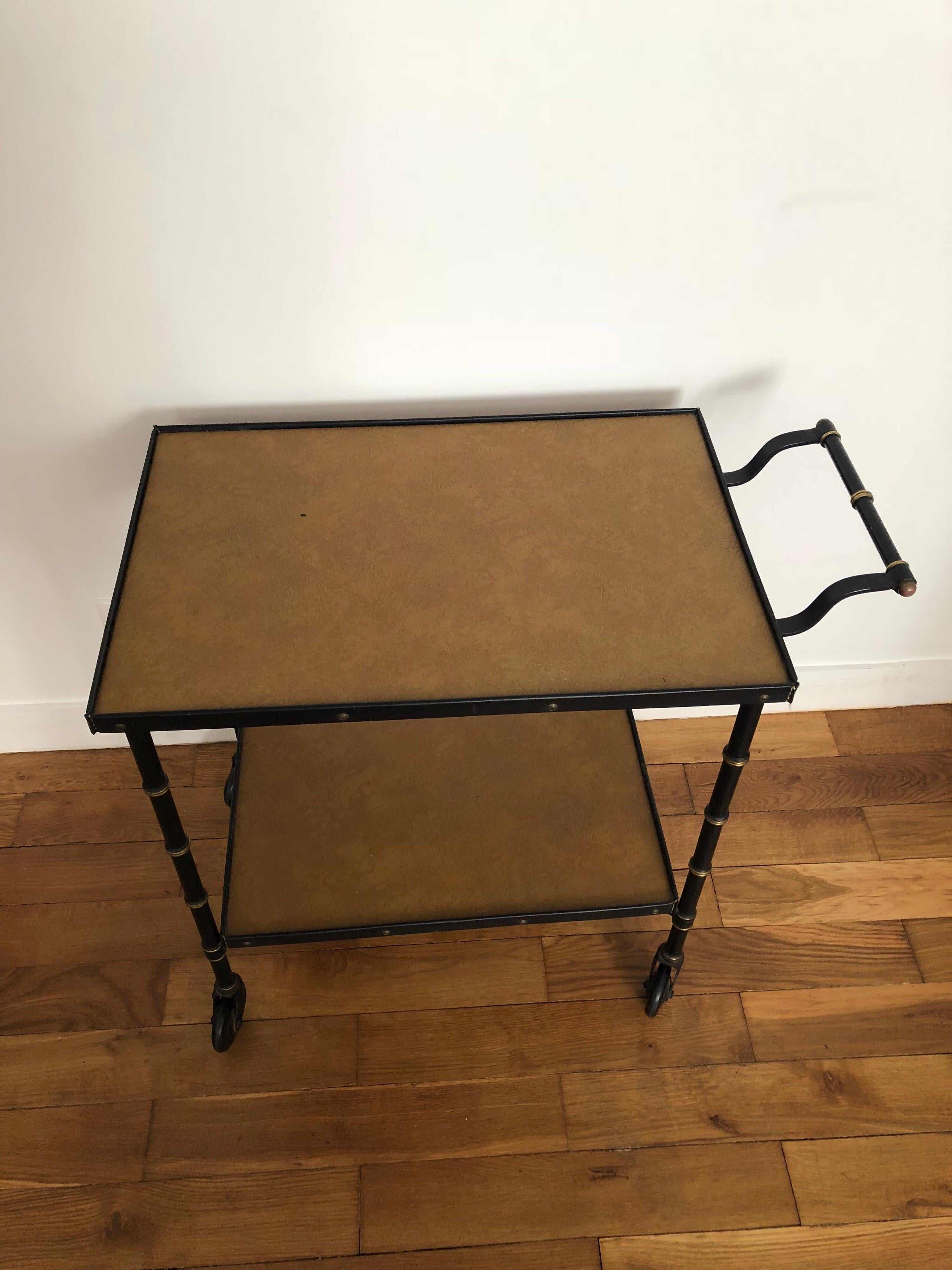 Jacques Adnet bar cart
The belt of the two trays are in black leather.
The two top trays are in light brown faux leather.
The structure is in black metal decorated with brass rings,
circa 1950.
Very good original condition.
Measures:
Long 73