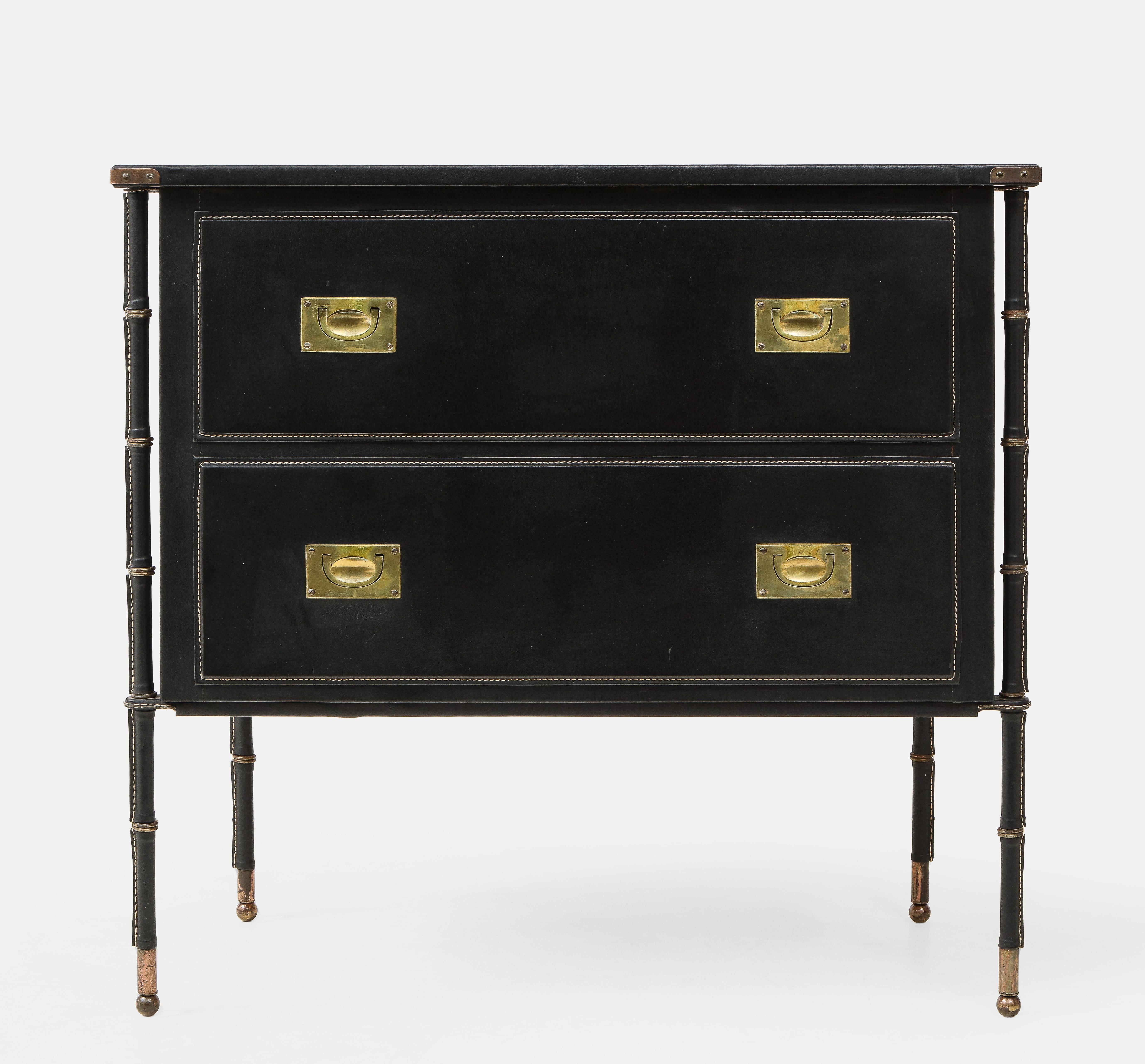 Jacques Adnet rare two-drawer commode, dresser or chest of drawers covered in black saddle-stitched skaï with faux bamboo legs and brass drawer pulls, France, 1950s. This collector's commode is in excellent condition and is free of tears or other