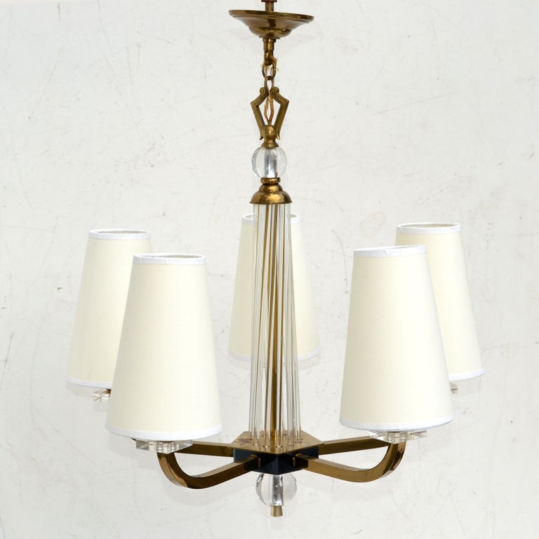 Superb Jacques Adnet Mid-Century Modern chandelier 2 patina brass, gunmetal and glass rods. Sold with off white cone shades.
Shade measures: height 7.5 inches x top diameter 3 inches x bottom diameter 5 inches.
In working condition and takes 5