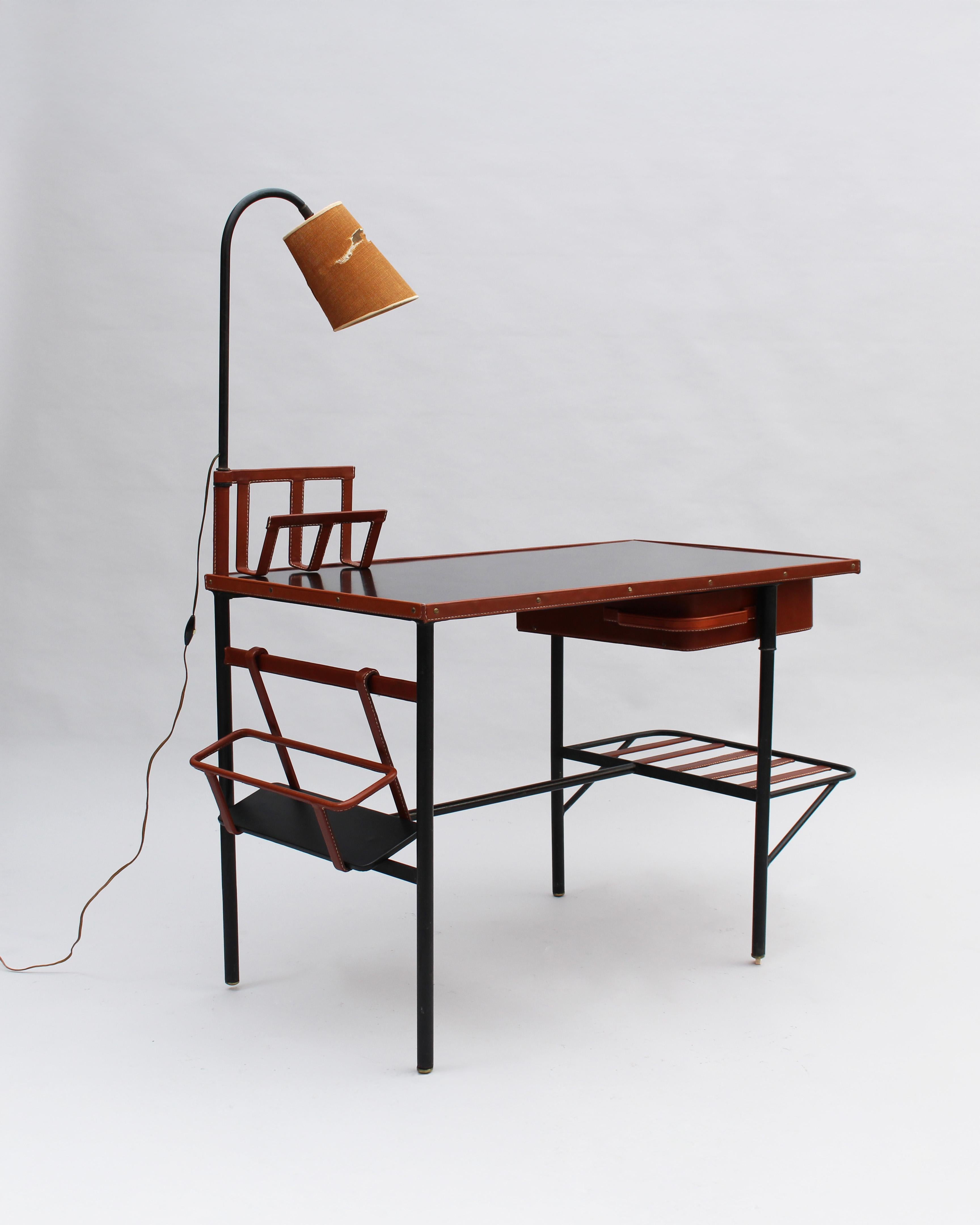 Jacques Adnet - Très beau bureau rectangulaire et lampe du milieu du siècle dernier, avec une base en métal laqué noir, un tiroir pivotant recouvert de cuir, 
porte-courrier en cuir piqué, étagère pour porte-documents et panier à bouteilles