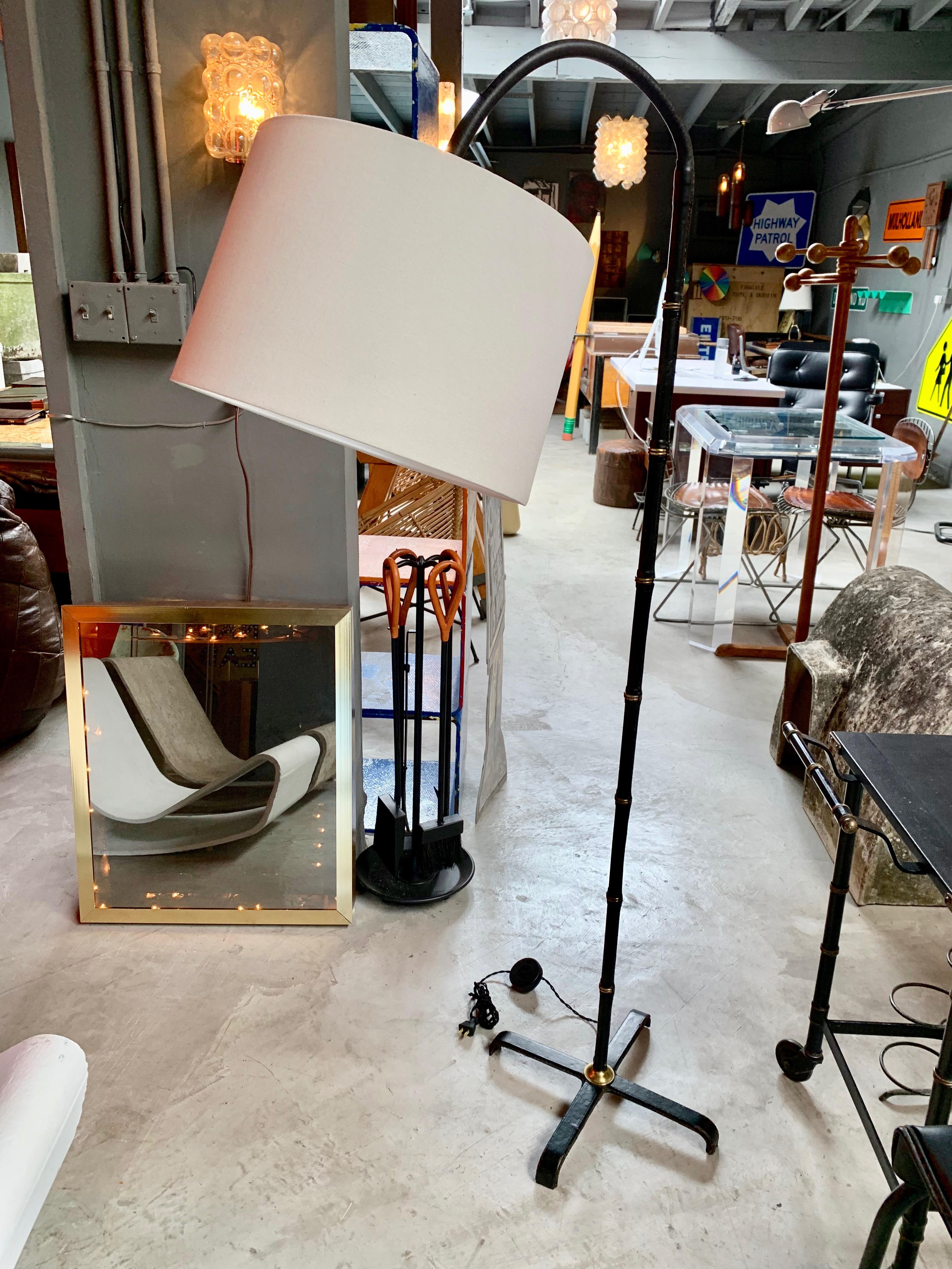 Stunning leather floor lamp by French designer Jacques Adnet. Arcing neck of lamp is movable to multiple positions. Beautiful patina to black leather with signature Adnet contrast stitching. Entire lamp is wrapped in leather. Newly wired. New linen