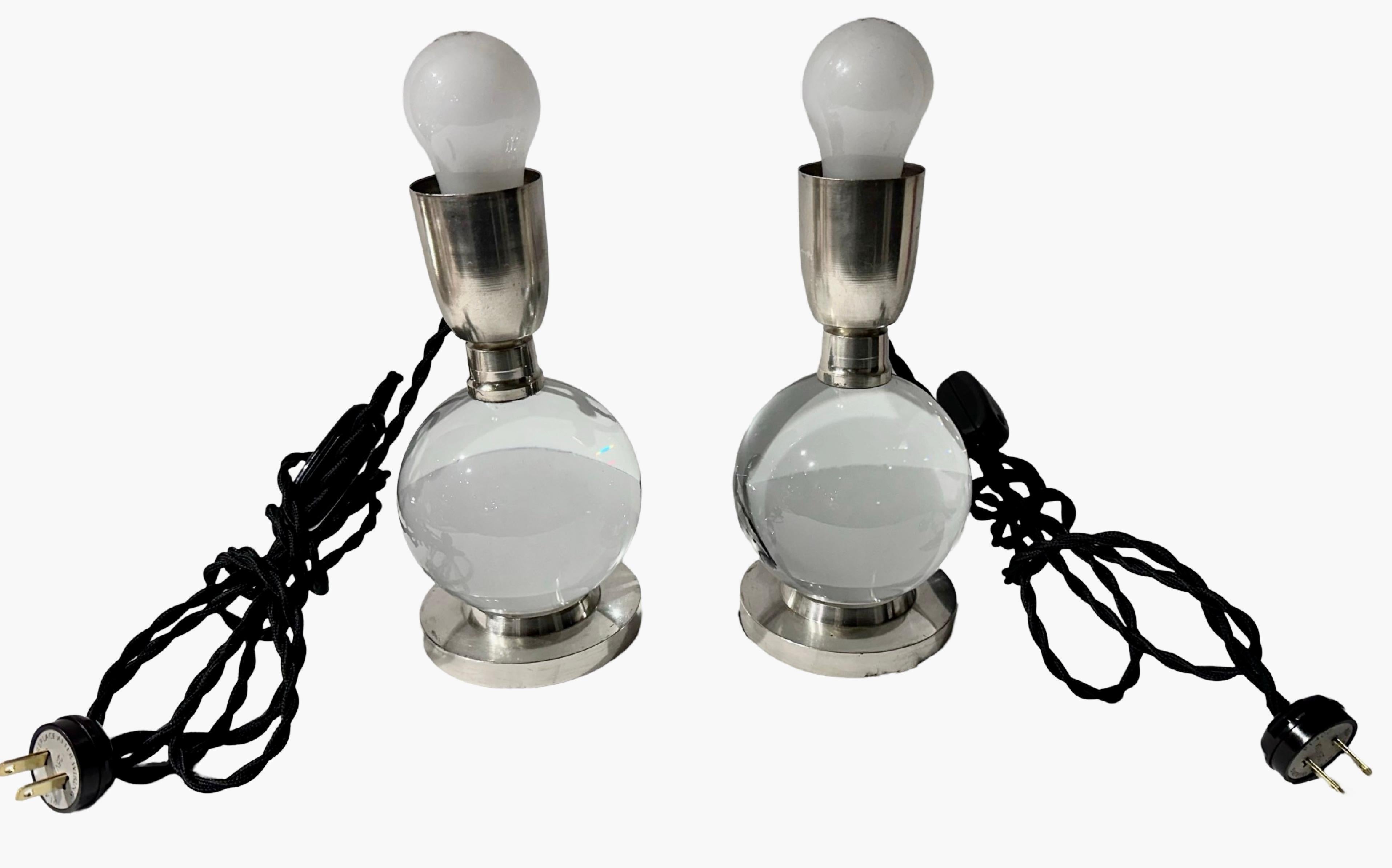 A modernist pair of Jacques Adnet lamps, designed for the Baccarat company, feature clear crystal and a nickel base. The adjustable ball allows for various positions. These lamps are dated back to the 1930s and are documented in the Adnet book