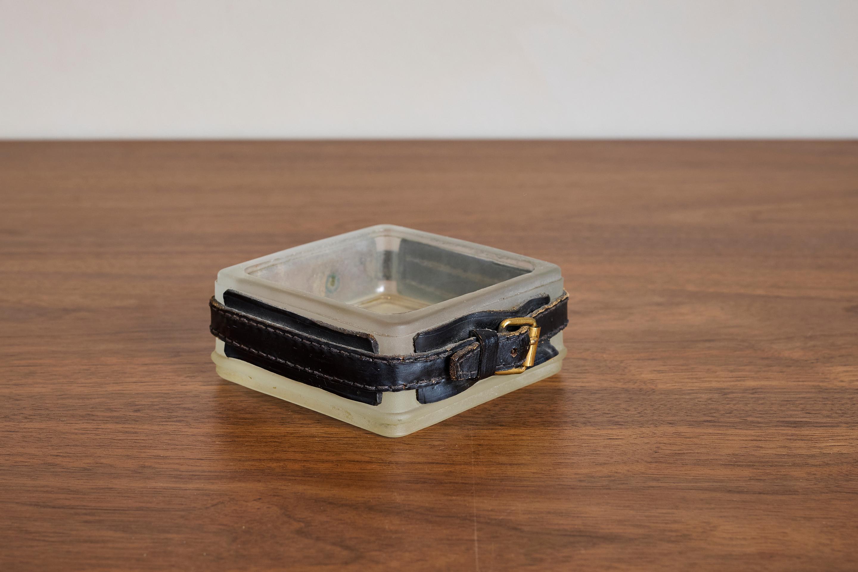 Handsome glass ashtray with leather belting and signature contrast stitching and brass buckle 

France 1940s.