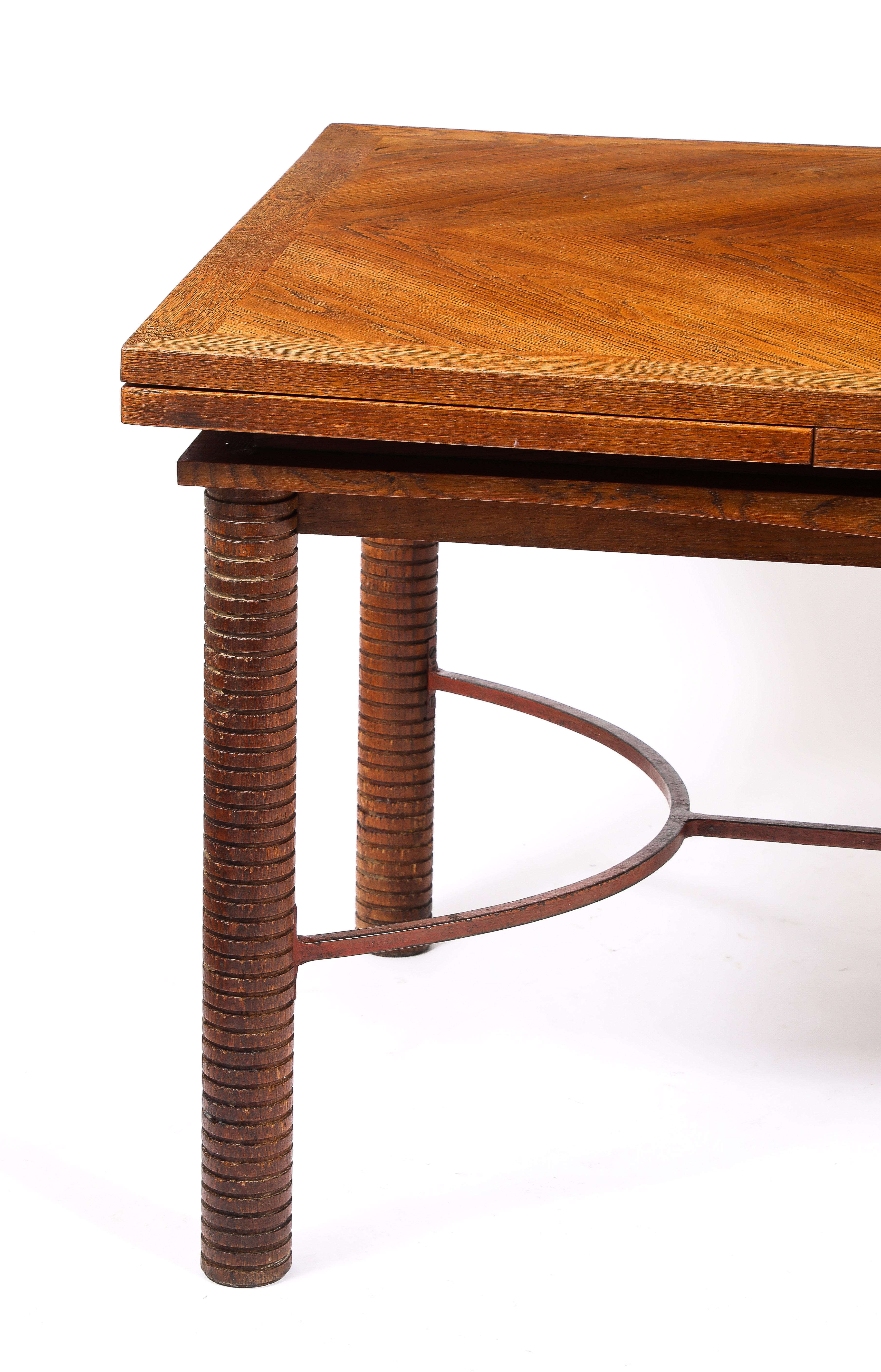 Oak and wrought iron extendable dining table by Jacques Adnet. Of note is the marquetry top with built-in leaves that simply slide out. It also features an Elegant double curved stretcher and grooved legs.

100'' Open
