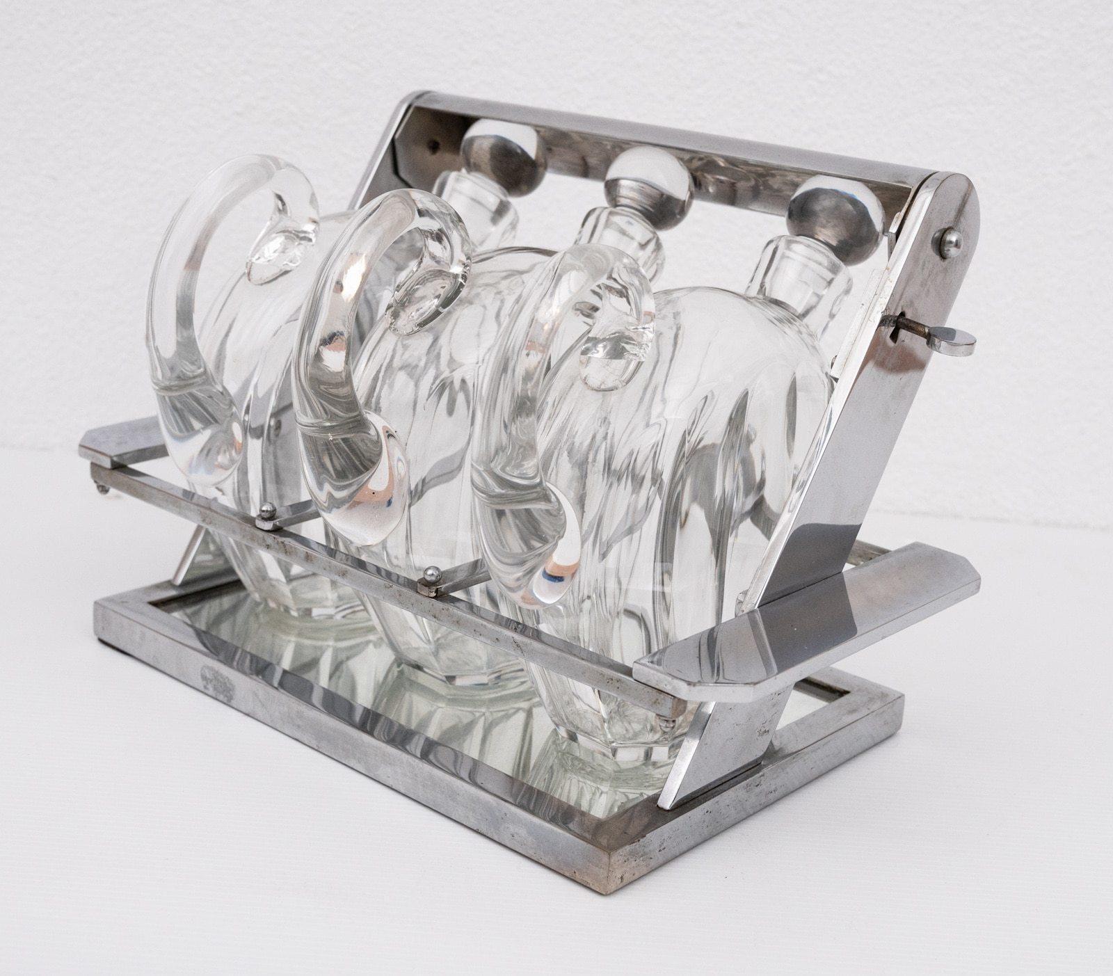 Art Deco period modernist Tanatalus attributed to Jacques Adnet. Complosed of a nickel-plated structure containing 3 carafes by Baccarat with cut sides and complete with handle and stopper. The top of the frame contains closing system and side grip