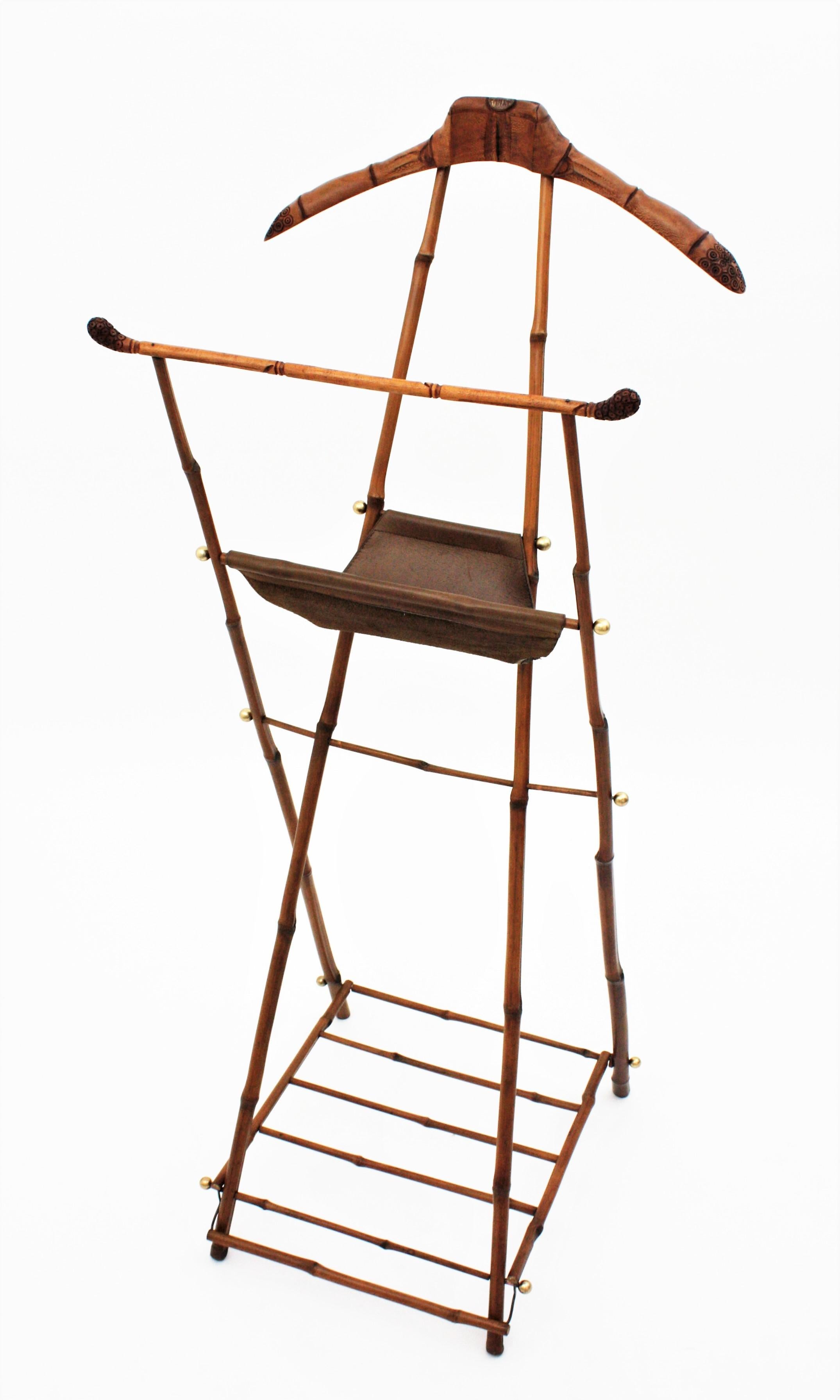 Gorgeous bamboo, wood and leather folding valet with brass accents. Attributed to Jacques Adnet, France, 1950s
This outstanding valet or coat stand is entirely made by hand with bamboo canes and carved wood. It has a leather folding stand and brass