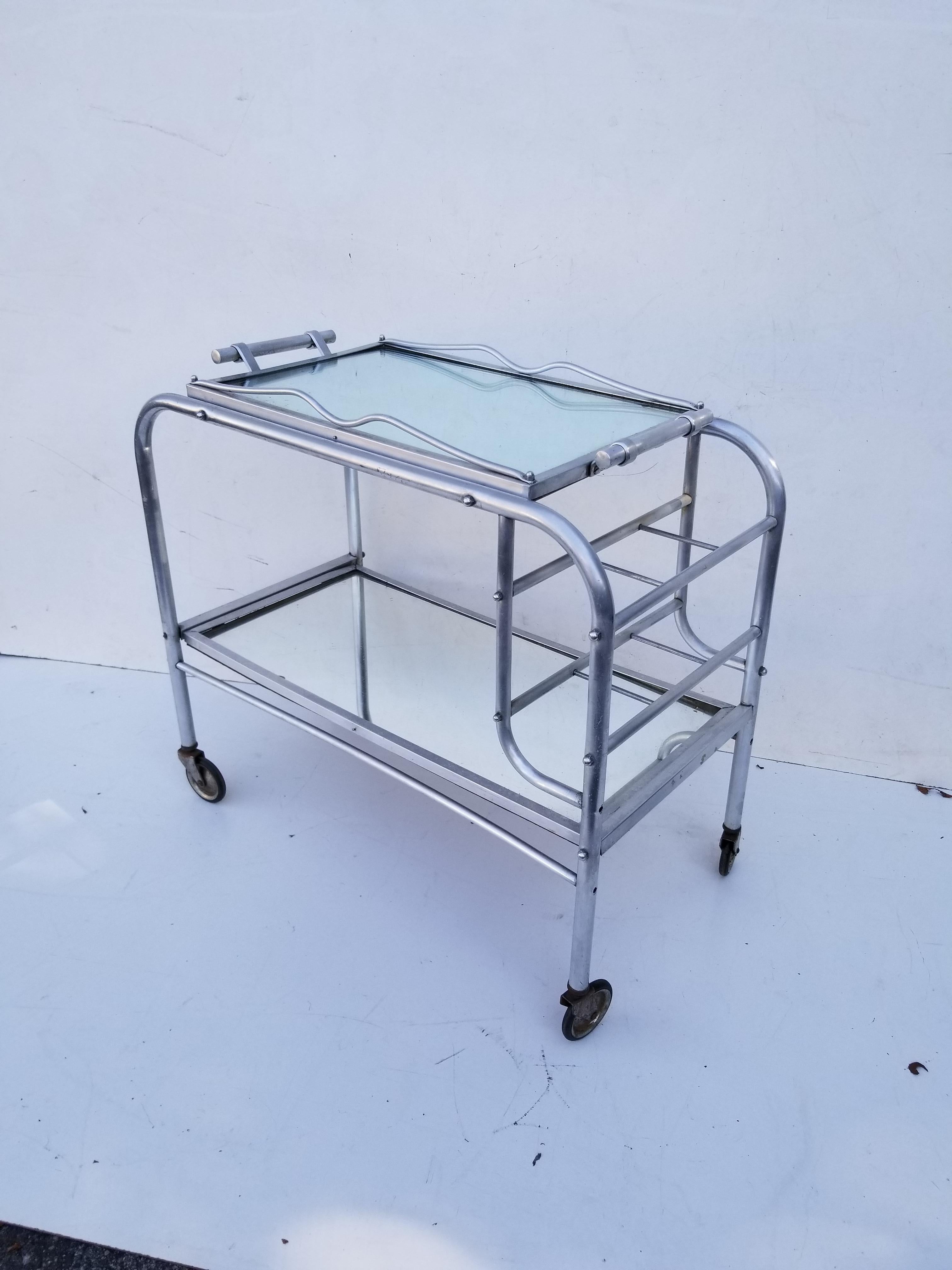 Jacques Adnet 2-tier bar cart, removable top mirror tray.
Very good condition, wheels in good condition.
Tray dimensions: 24 / 15 inches.

      