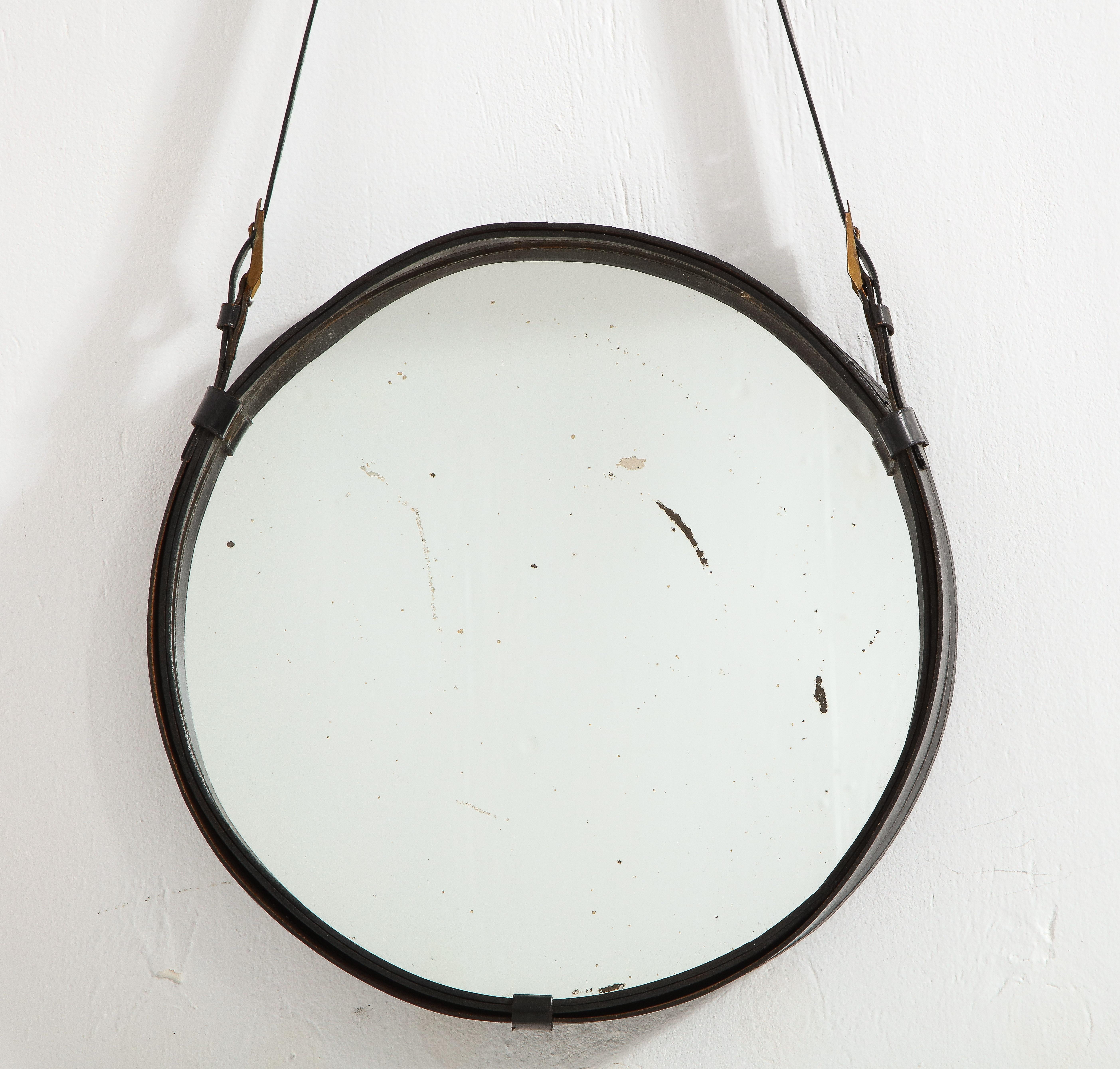 Jacques Adnet style leather covered mirror hanging on a leather belt.