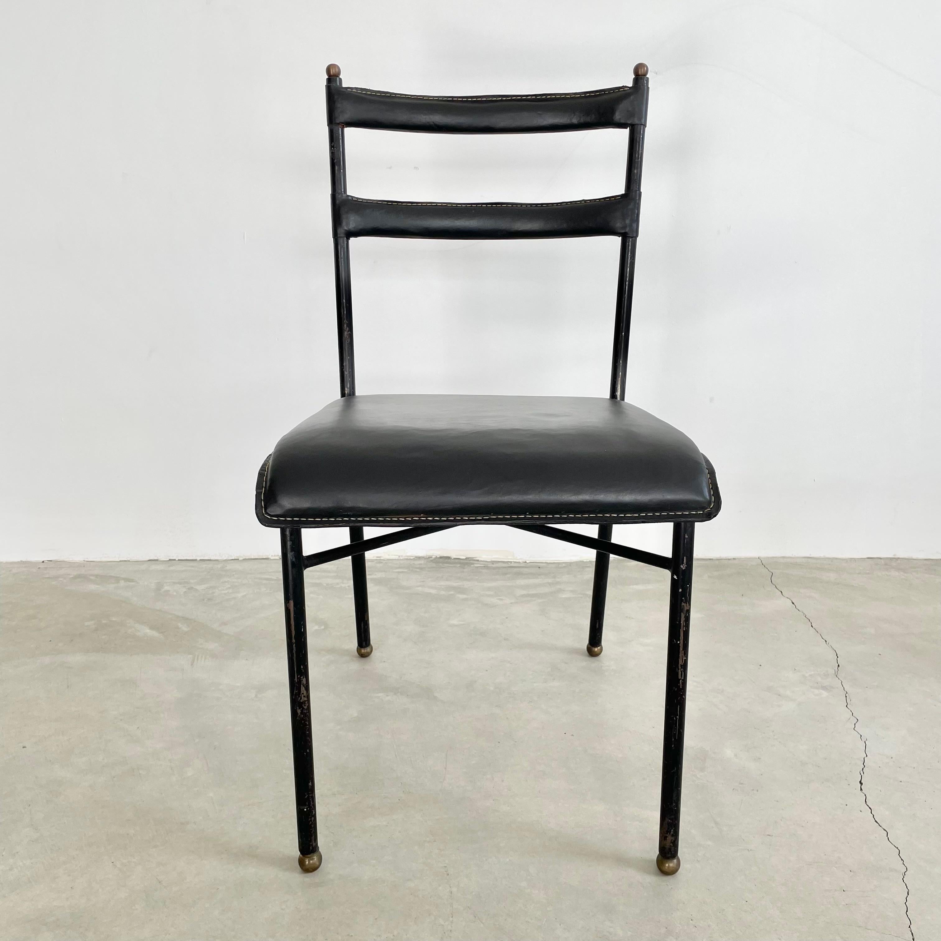 Stunning black leather chair by French designer Jacques Adnet. Black metal frame with its legs ending in brass ball feet. Brass balls adorn the top of the frame as well. Thick leather seat and backrests hand-stitched in the characteristic Adnet