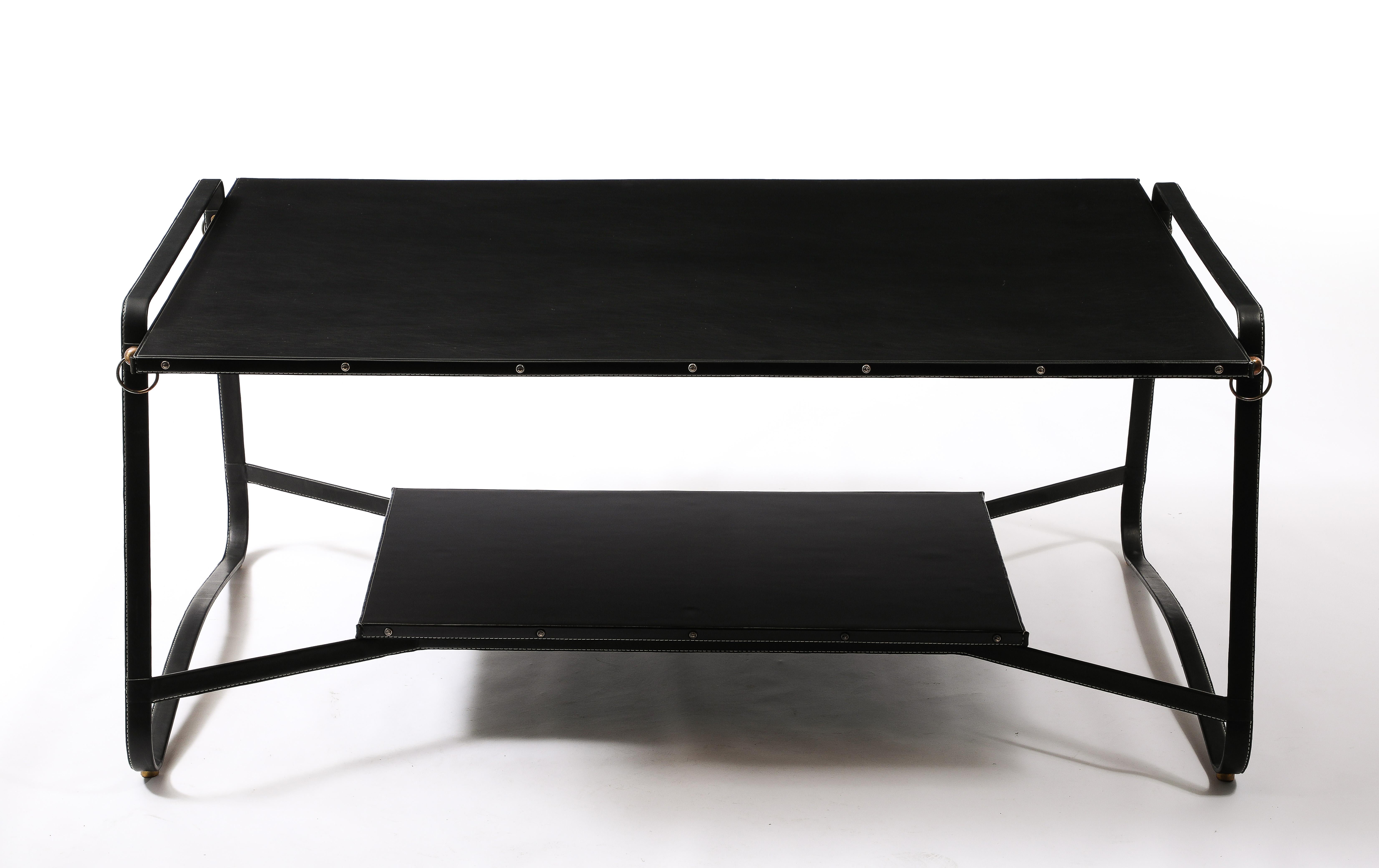 Large coffee tables in stitched leather and brass, the top is covered in leather and the second level in a laminate.

32x55x23. Top Height is 21