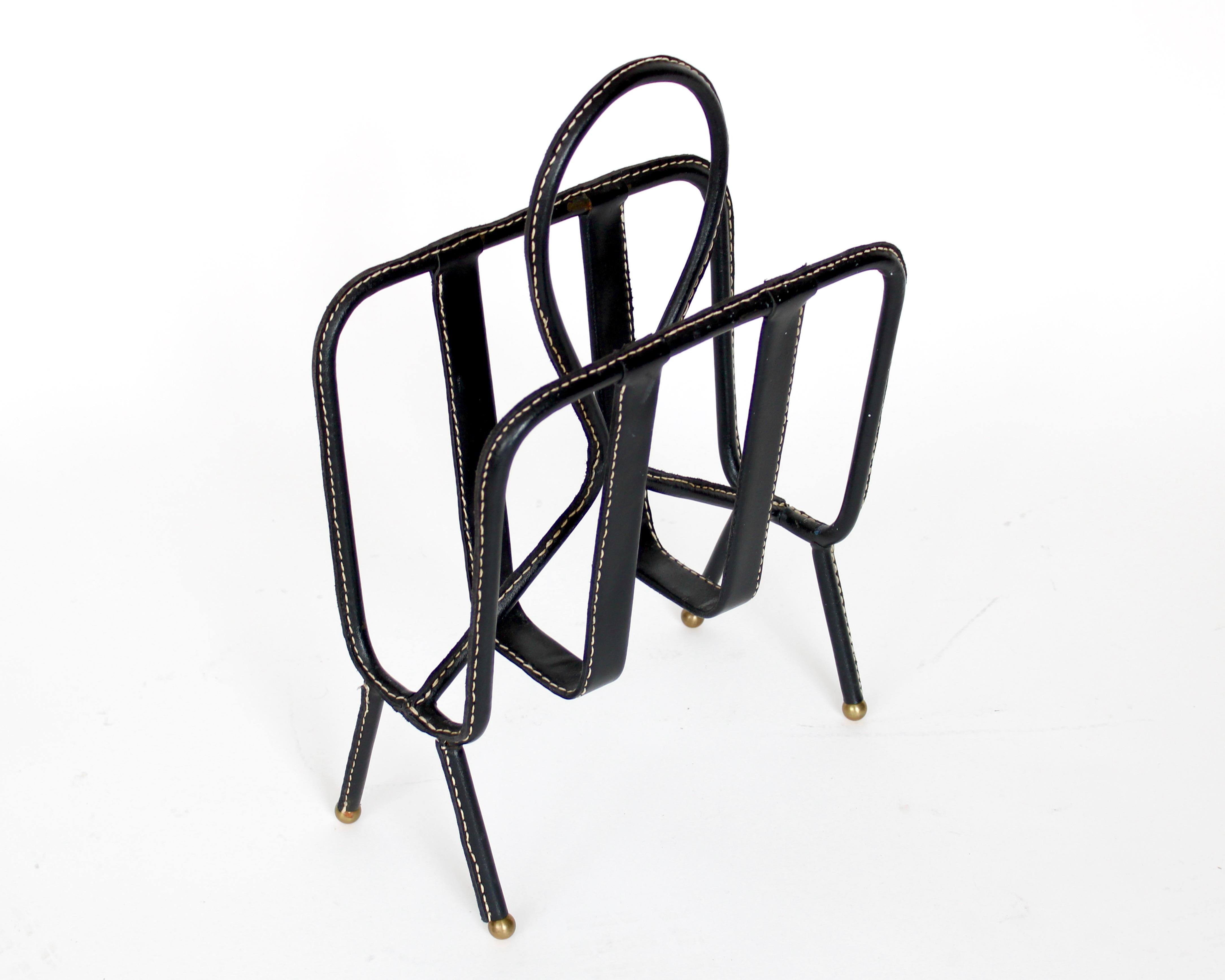 Black leather with original cream stitching magazine holder by Jacques Adnet. On brass ball feet. 18.25