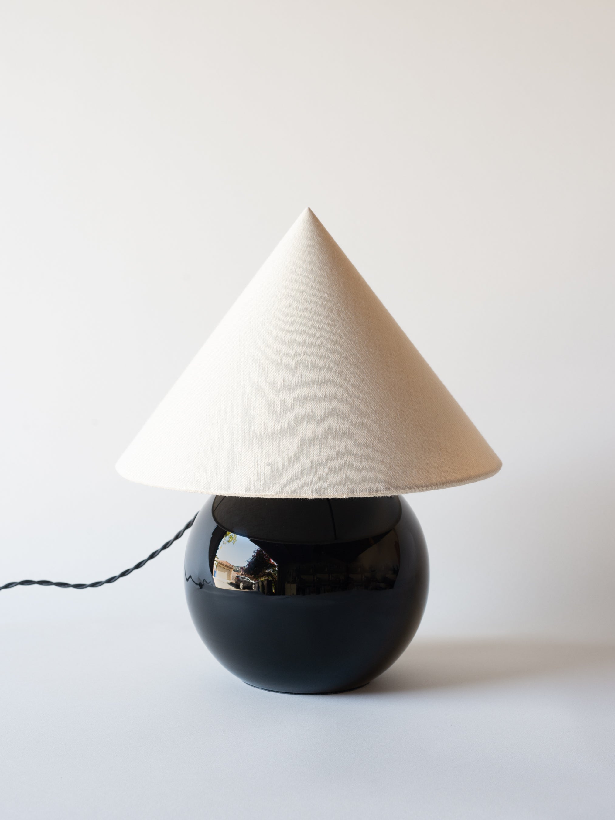 A spherical black glass table lamp by Jacques Adnet circa 1940. Rewired for US outlets and fitted with a custom white linen shade with stitched black suede edge detail. 


