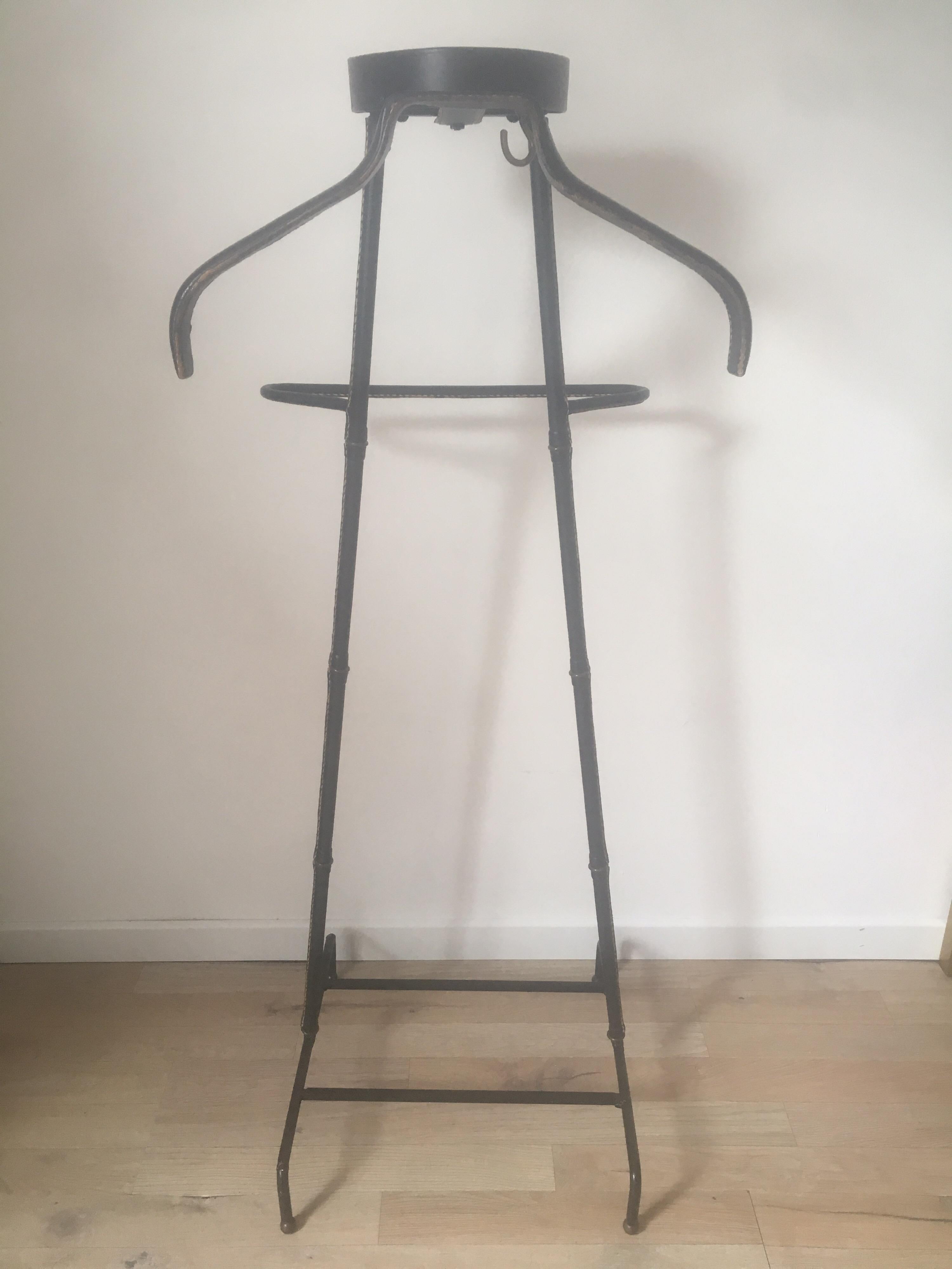 Beautiful black stitched leather valet designed by Jacques Adnet in France in 1950s.
This rare model of valet de nuit, fully leather-wrapped, has 2 arms to wear shirts and pants. It rests on a bamboo-shaped base, brass rings and saddle-stitched