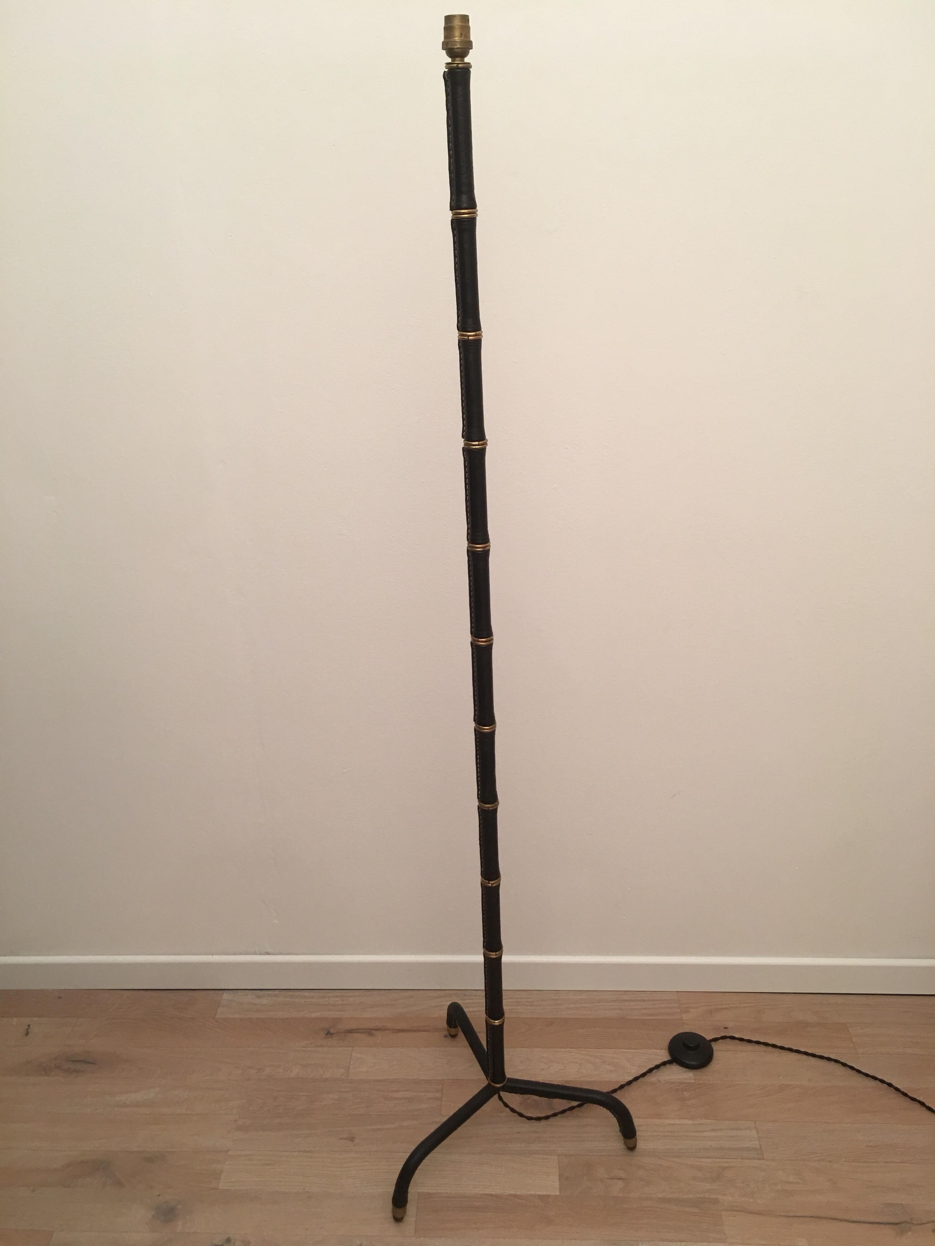 Elegant black stitched leather floor lamp designed by Jacques Adnet in France in 1950s. The bamboo form floor lamp, alternating stitched leather and brass rings, rest on a tripode base wrapped in black leather.
Original French bayonet socket and