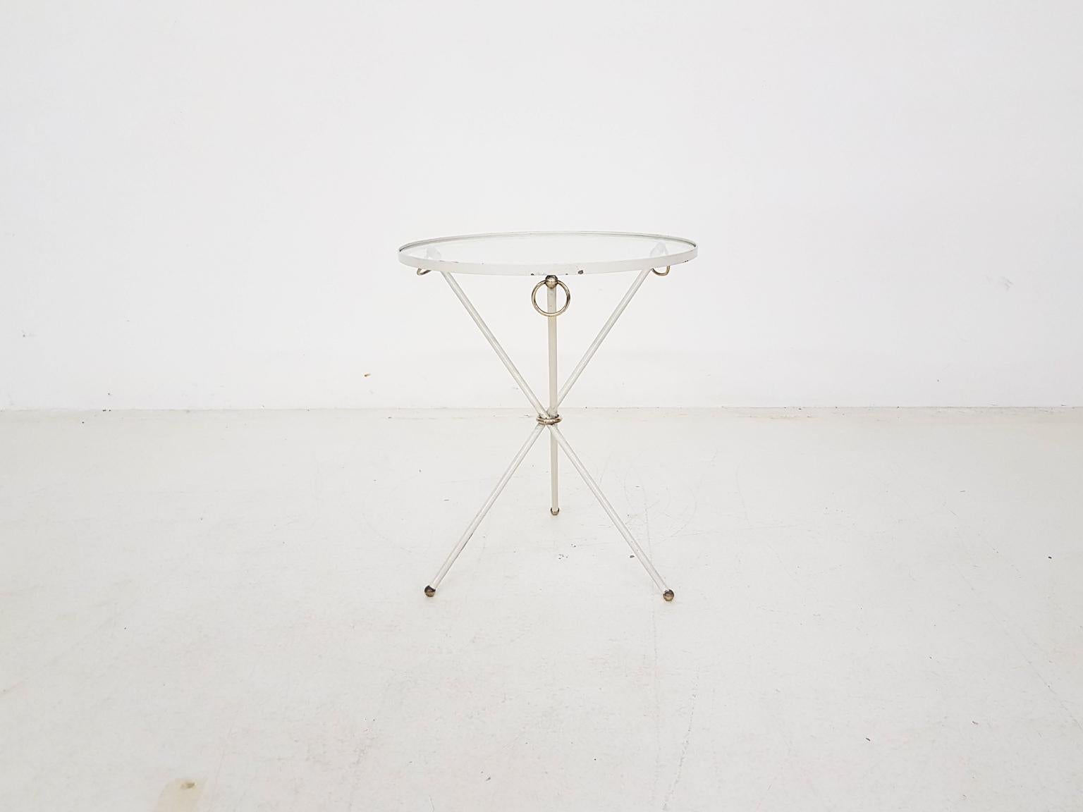 White round metal side table with glass top and brass decorative rings and brass feet. Designed by the legendary French luxury designer Jacques Adnet in the midcentury.

We received this item from the 1st owner together with more Jacques Adnet