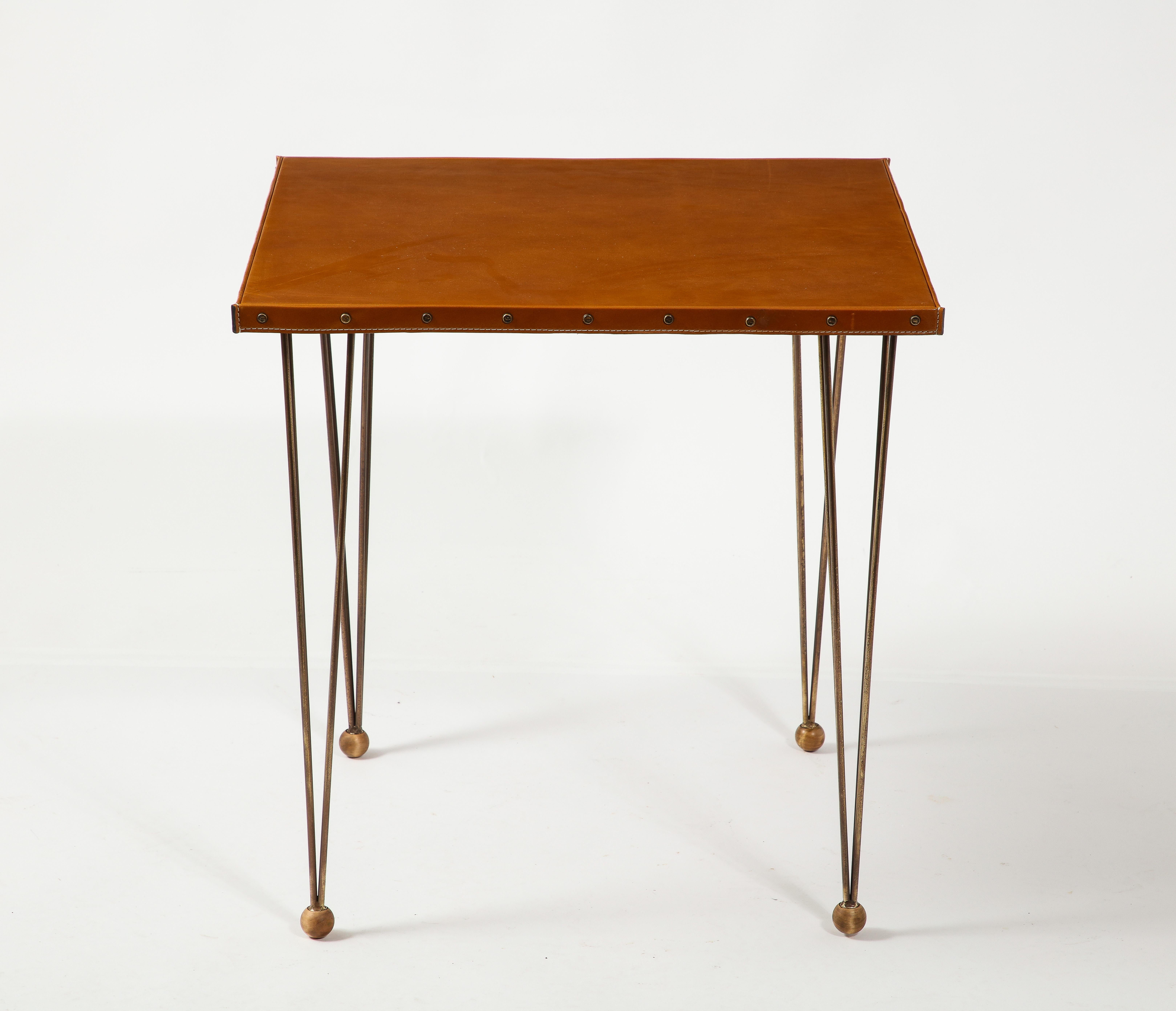 
Large end table in stitched leather and patinated brass, the legs end on walnut balls and the tops have brass screws holding the trims.
