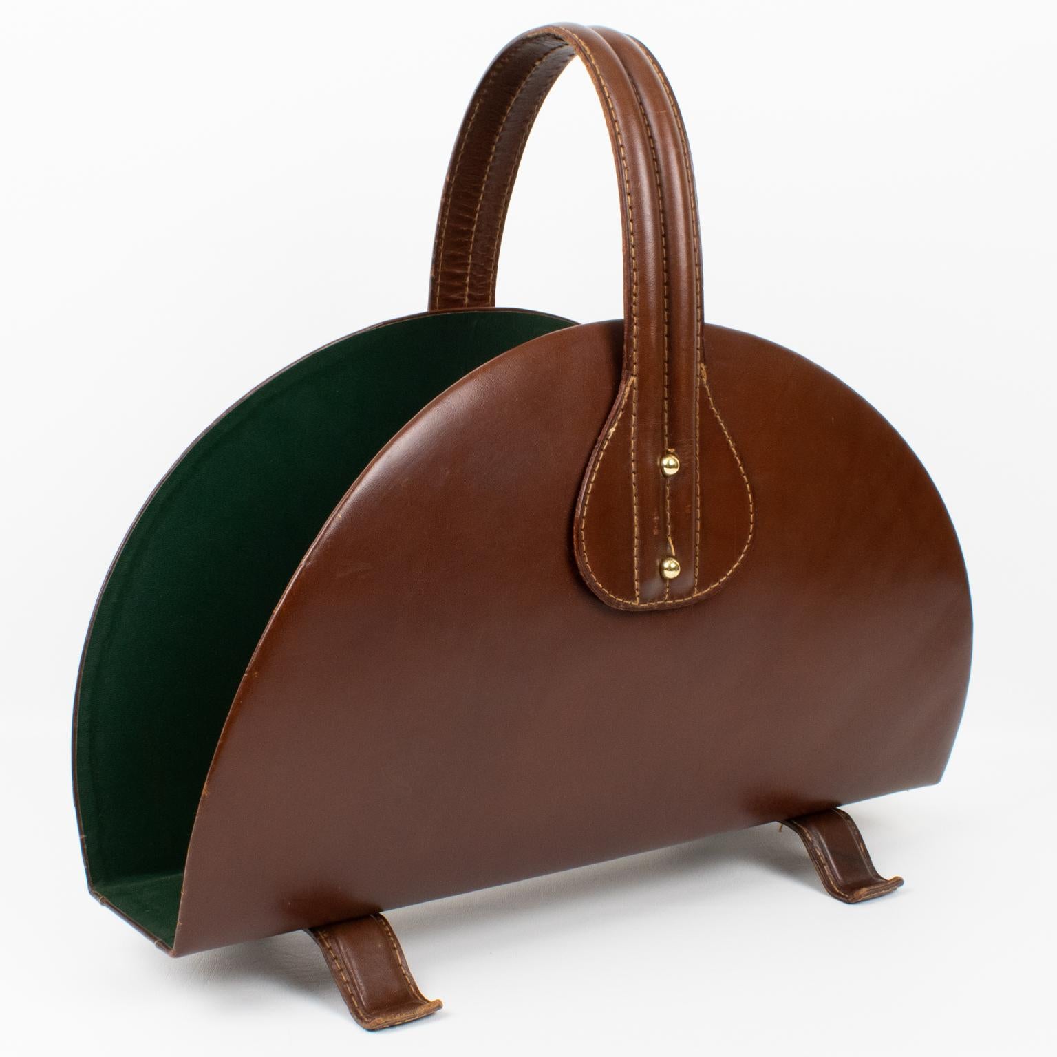 This exquisite magazine rack or holder was expertly designed by renowned French designer Jacques Adnet (1901 to 1984) in the 1950s. The item boasts a strikingly sleek and refined appearance, with its hand-stitched leather material in a warm and deep