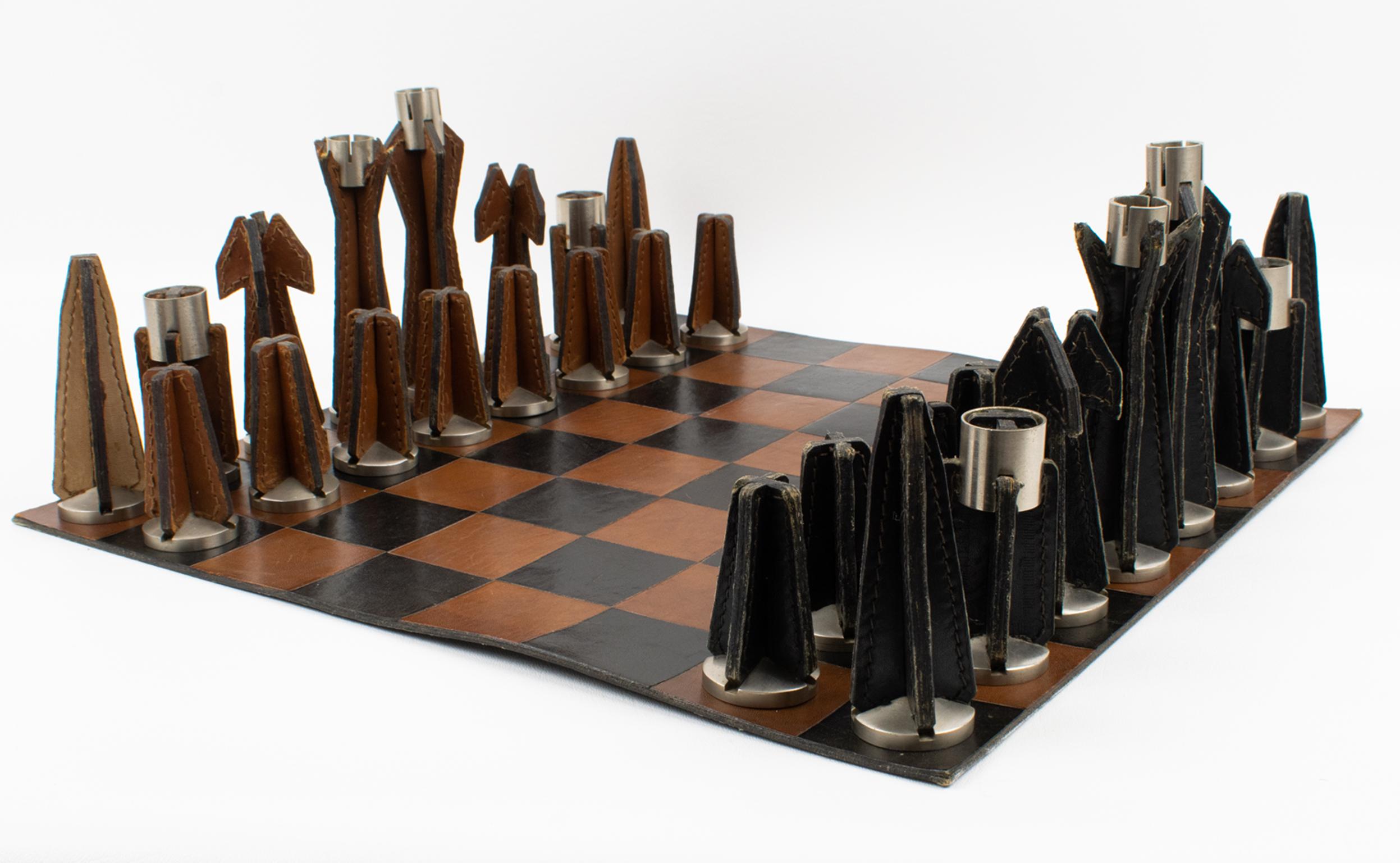 Ce superbe et rare échiquier original et son jeu de trente-deux pièces ont été conçus par le designer français Jacques Adnet (1901-1984) dans les années 1950. La planche en cuir bicolore présente trente-deux pièces. Chaque pièce porte la signature