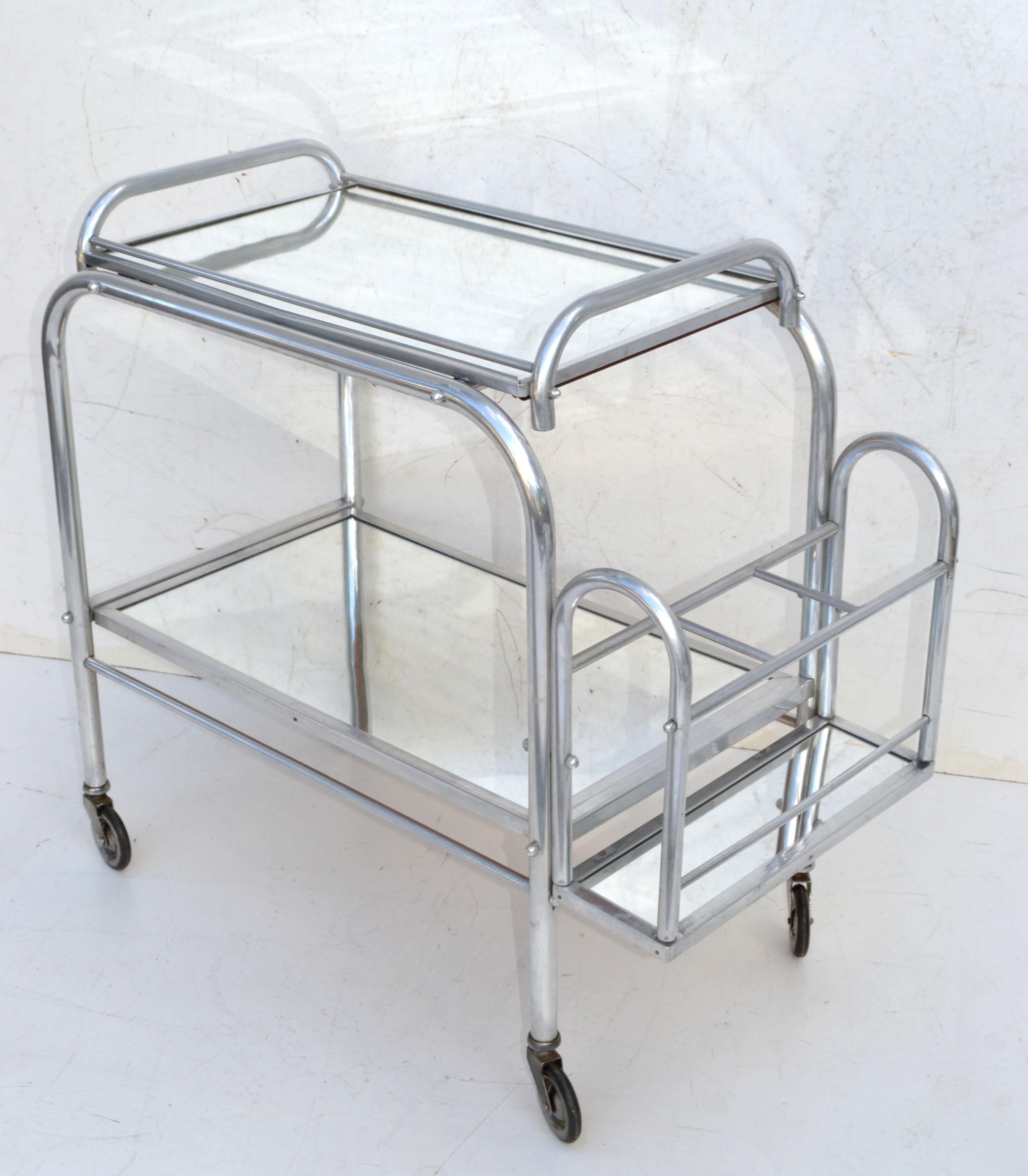 Jacques Adnet 2-tier bar cart, removable top mirror tray and bottle holder.
Very good original condition and wheels run smoothly.
Tray dimensions: 24 / 15 inches.
Space in between is 13 inches height.
Bottle holder measures: 12 x 5 inches.


