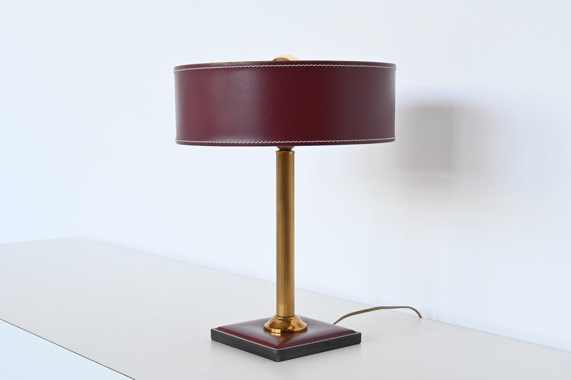 Very nice and highly decorative table lamp attributed by Jacques Adnet, France 1960. This leather clad table lamp has a square foot and a brass stem, the round shade is made of leather too. High quality stitching on this lamp. It is made in very